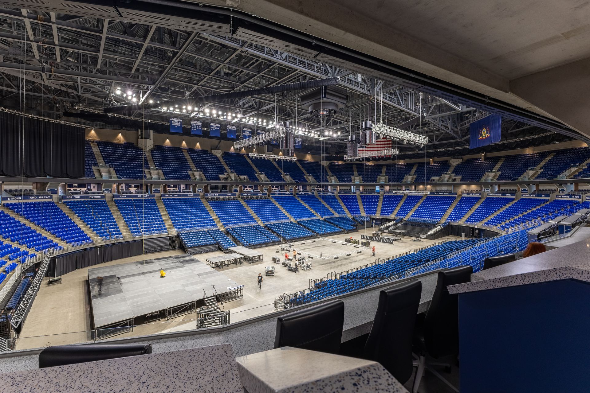 Bryce Jordan Center's empty indoor arena with blue seating and a covered central floor, viewed from the stands