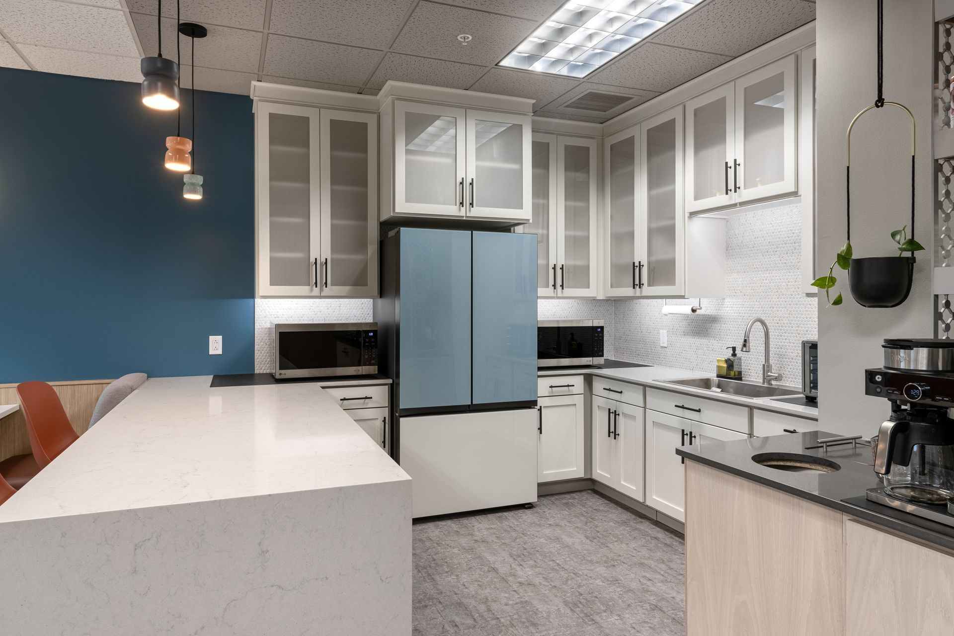 Penn State Earth and Engineering Sciences kitchen featuring white cabinets, a light blue refrigerator, and a large white island with a dark wall.