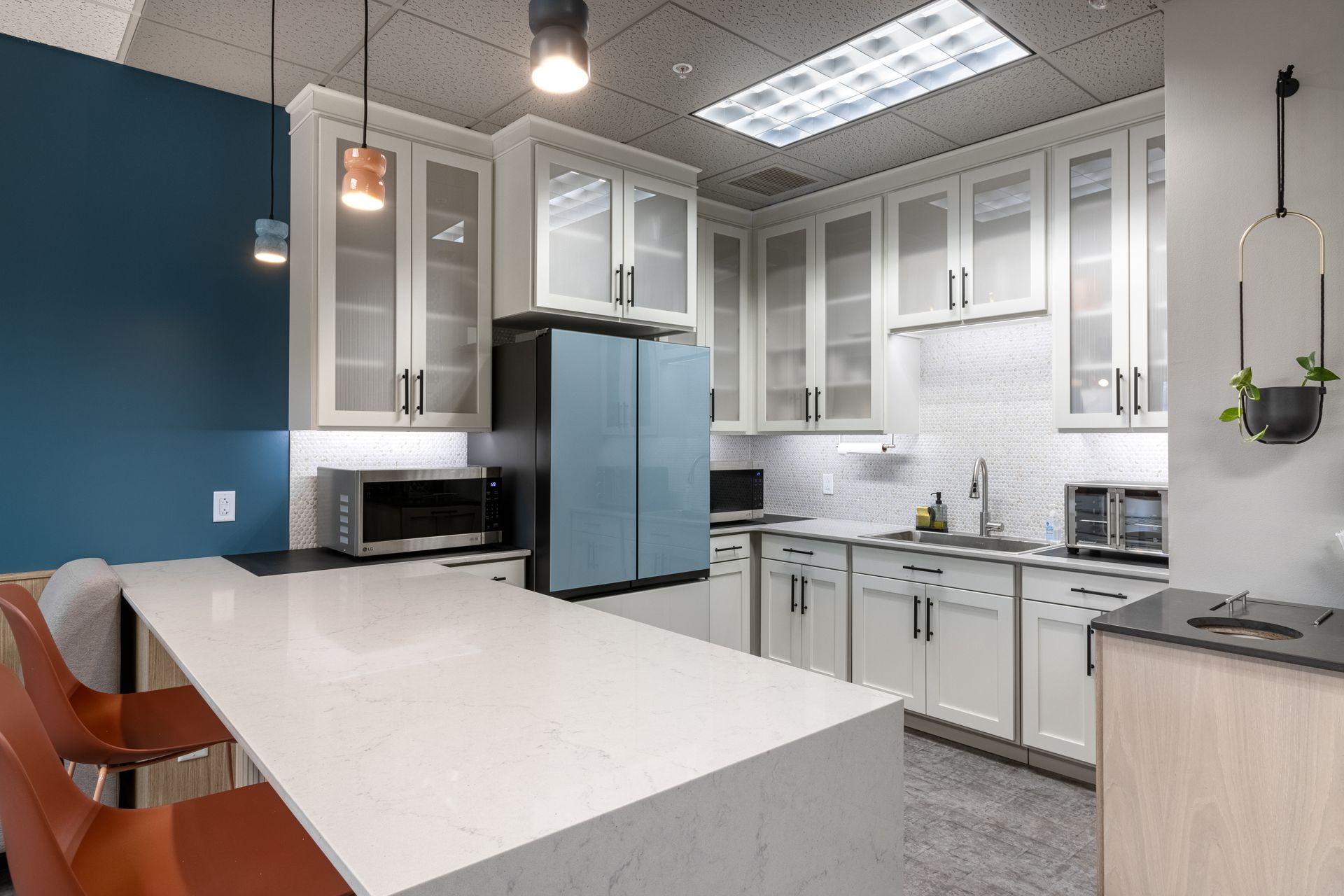 Penn State Earth and Engineering Sciences kitchen with white cabinetry, a large stone-topped island, a light blue refrigerator, and dark blue accent wall.