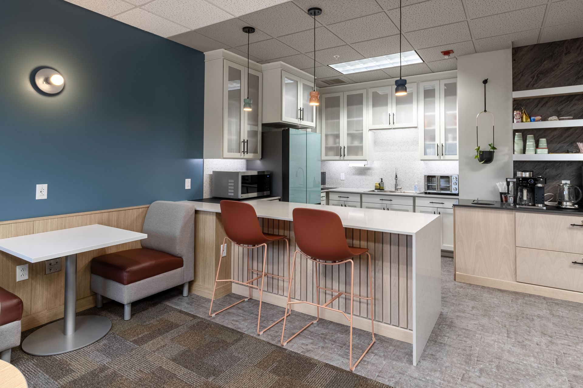Penn State Earth and Engineering Sciences kitchen with a small dining table, two red bar stools at a counter, and white kitchen cabinets.