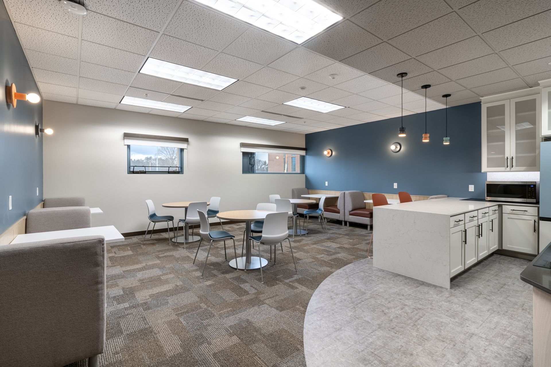 Penn State Earth and Engineering Sciences kitchen with a mix of booth seating, round tables, and a kitchenette with a white island.