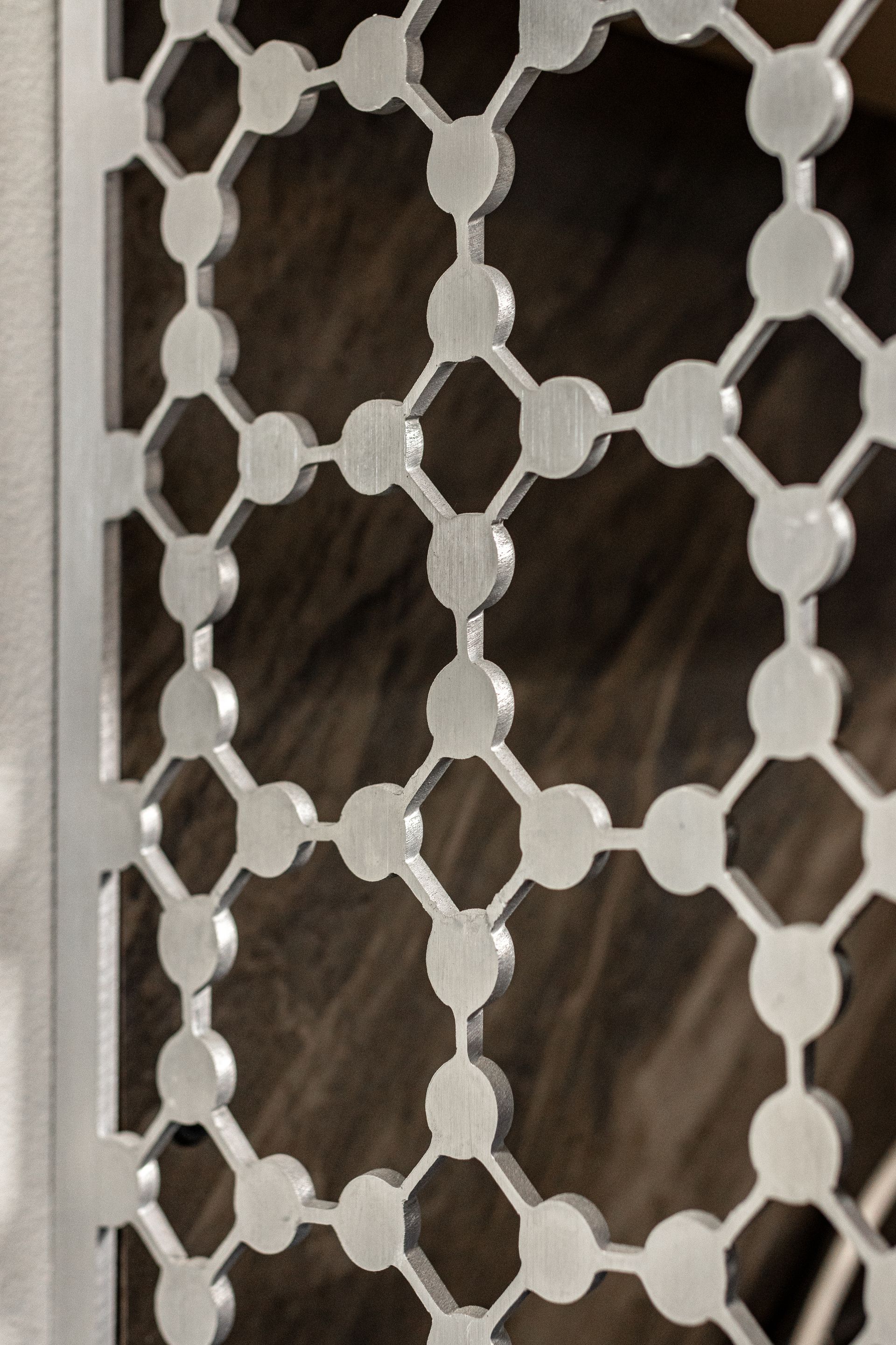 A decorative silver screen featuring a repeating geometric pattern of connected circles over a dark, textured background at Penn State Earth and Engineering Sciences kitchen.