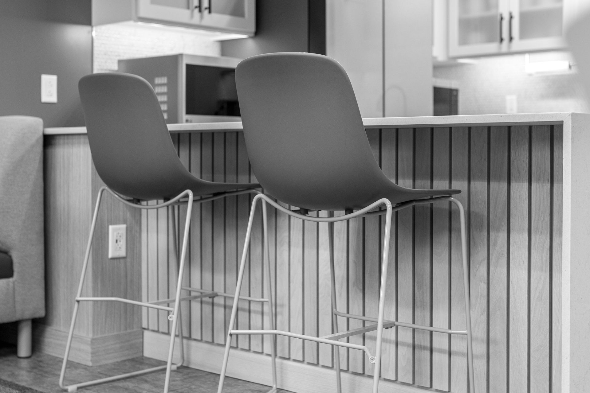 Two modern stools with curved seats and metal frames sit before a slatted kitchen counter.