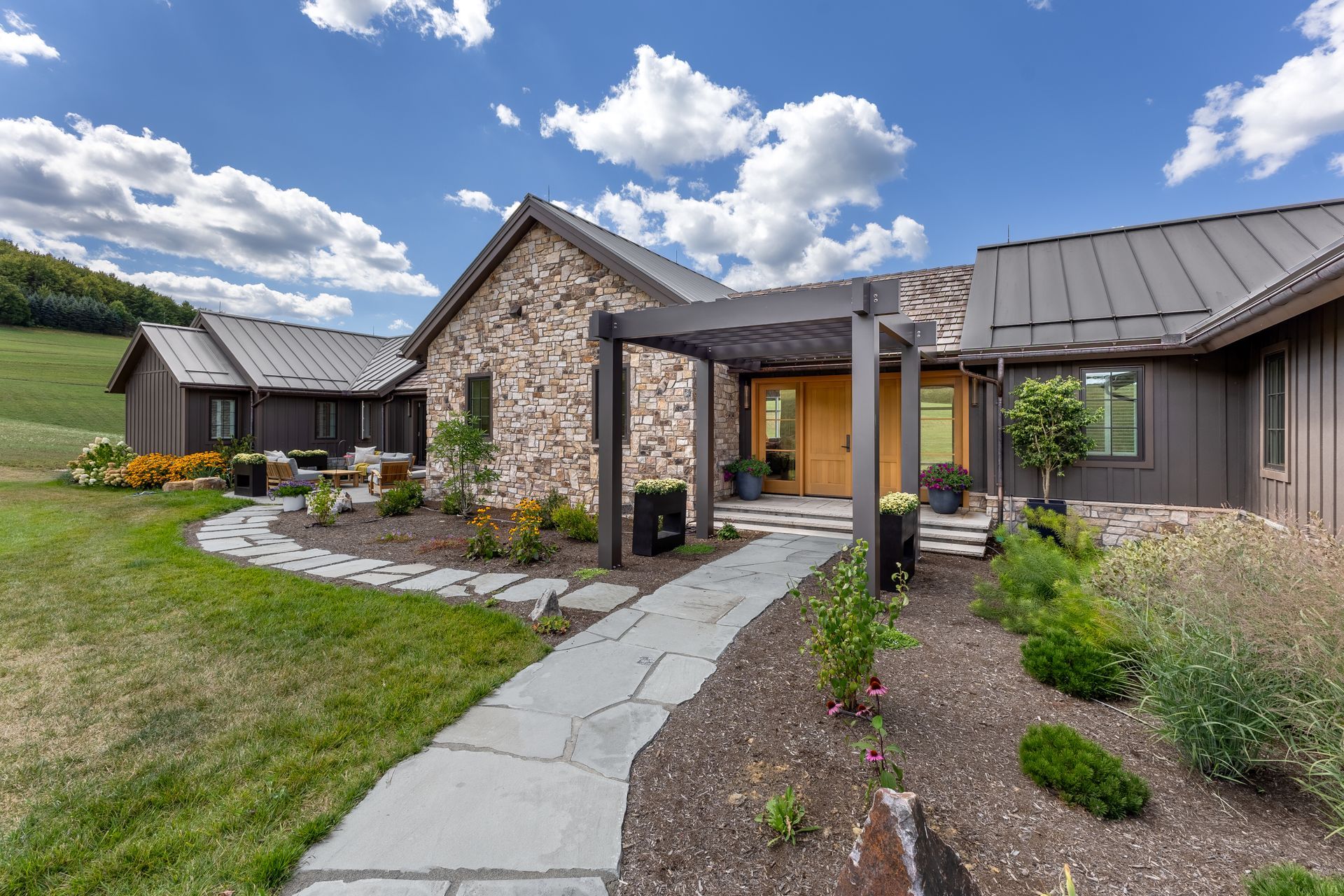 Stone house with a curved walkway, landscaped garden, and cloudy sky