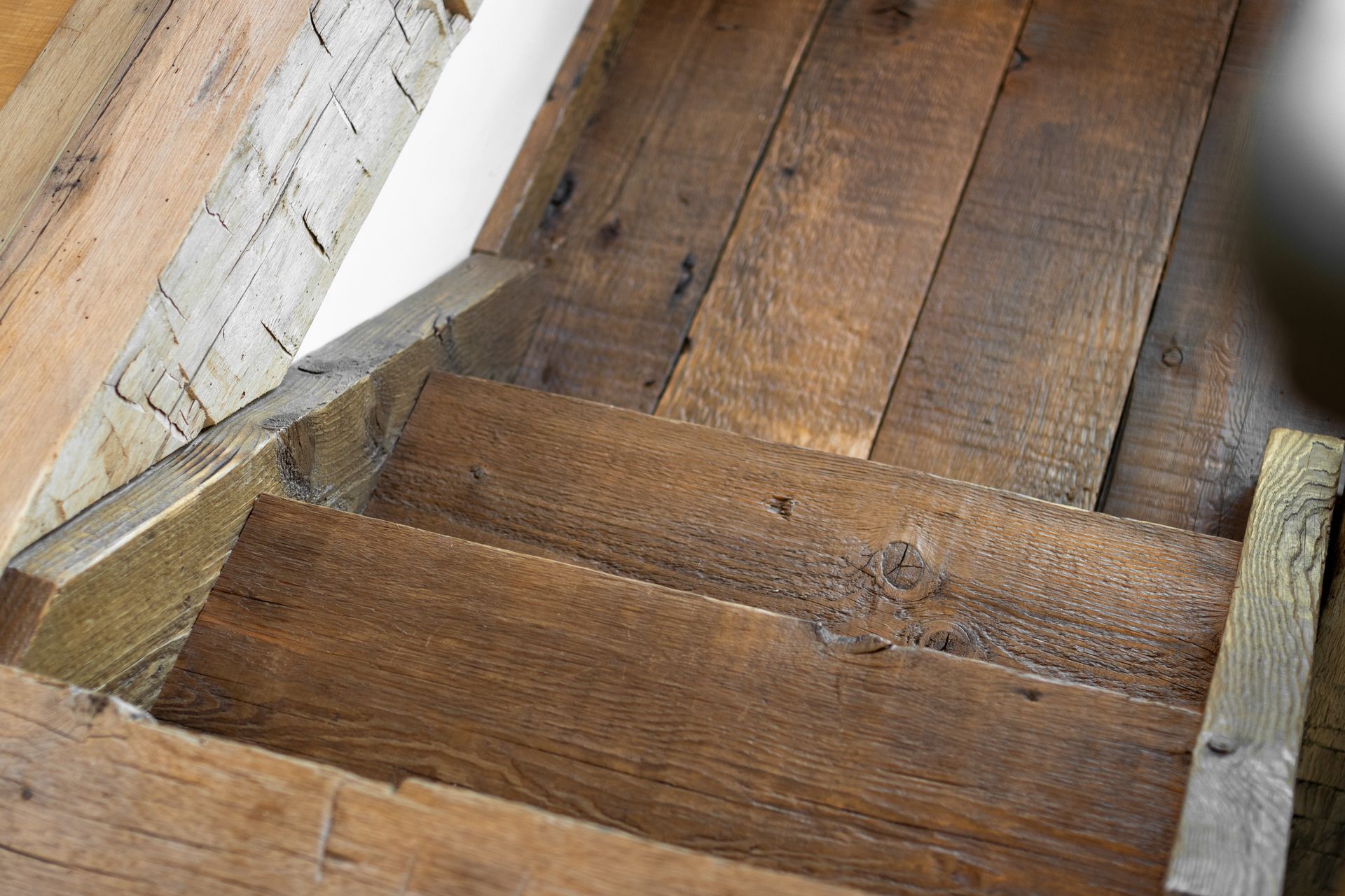 Close-up of rustic, weathered wooden stairs descending from a landing.