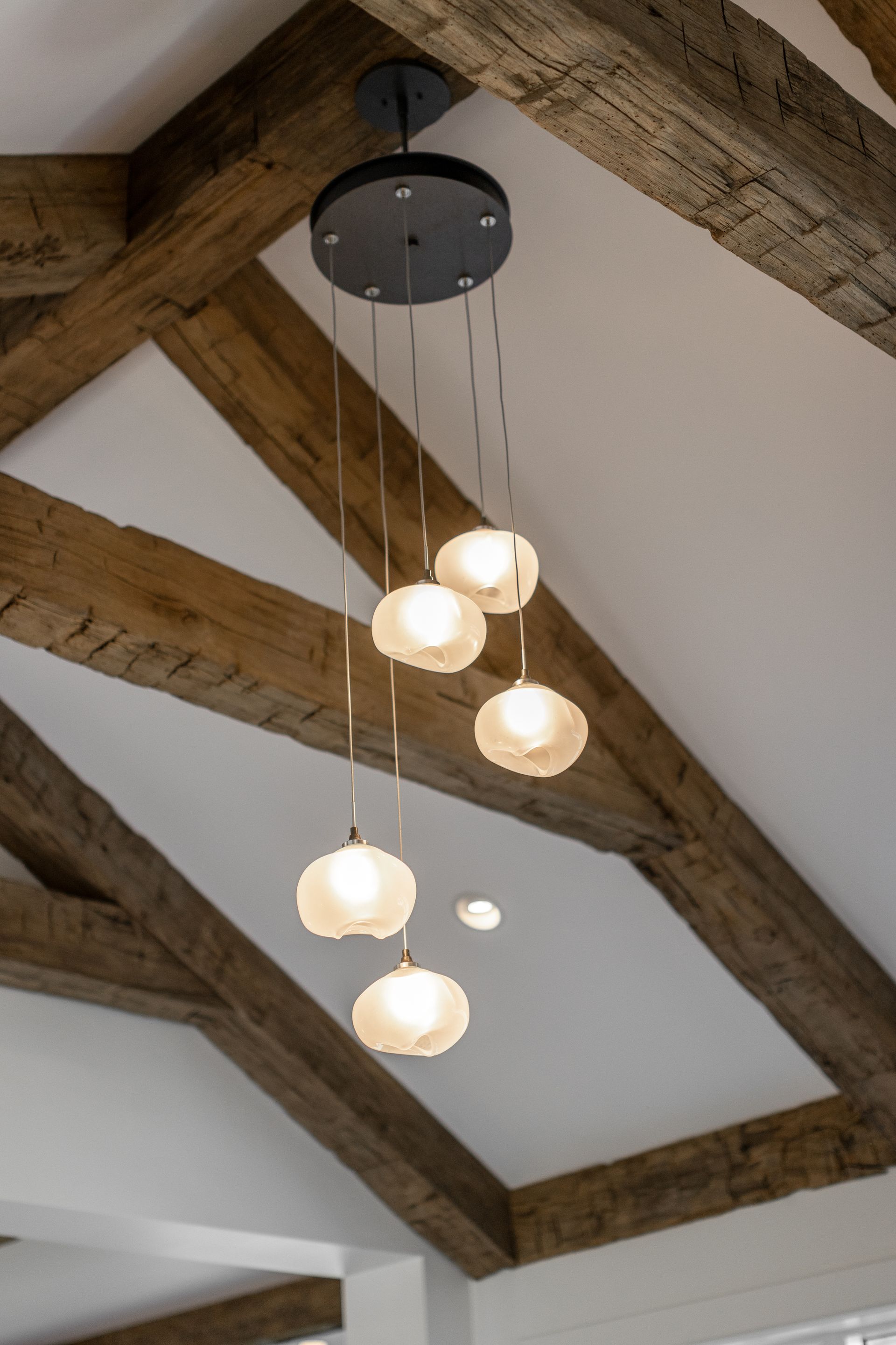 A modern multi-light pendant fixture with five glowing frosted glass globes suspended from a dark circular ceiling mount.