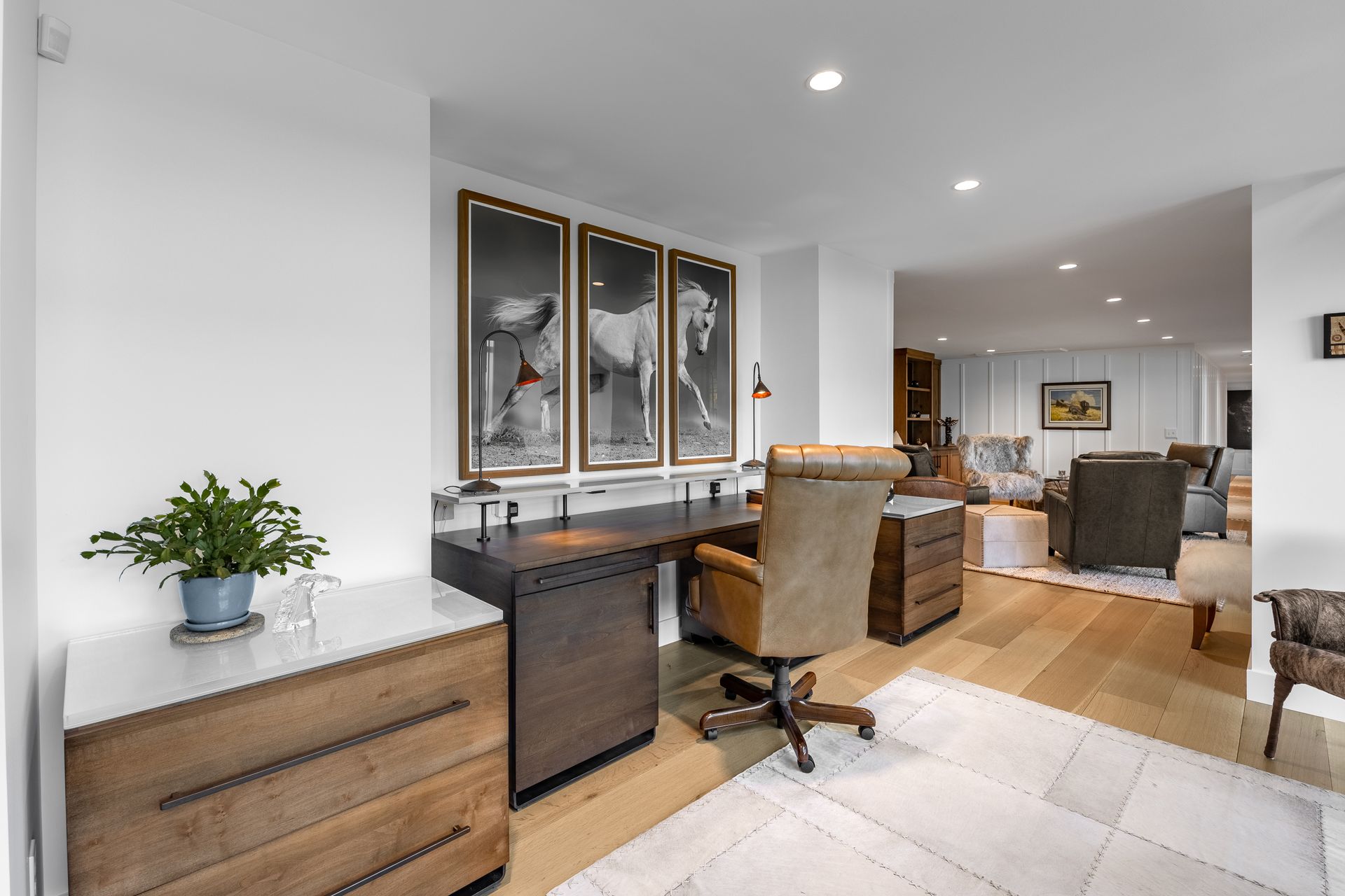 Modern open-concept living room and kitchen with wood cabinets, white walls, and tiled floor.