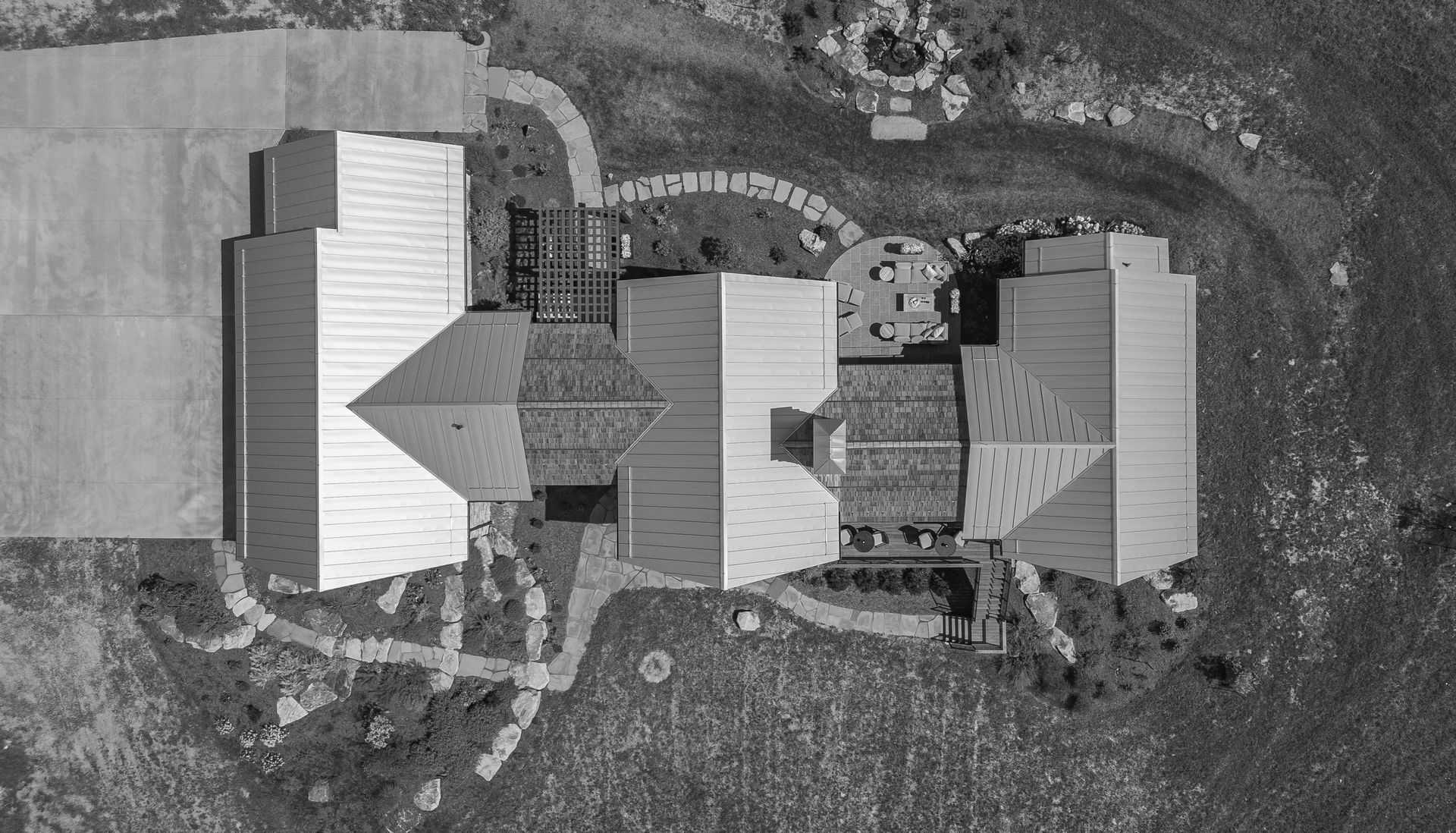 Aerial view of three light-roofed buildings connected by walkways on a grassy rural property