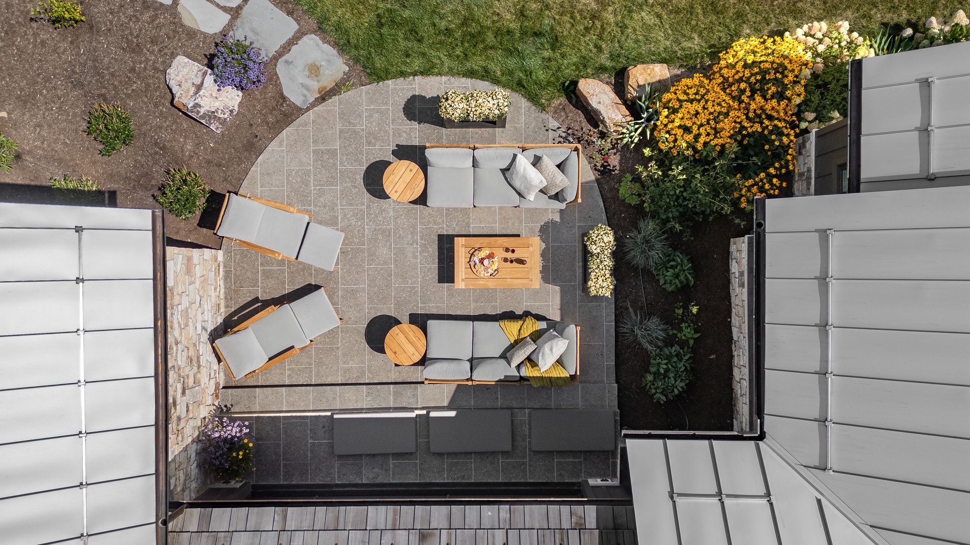 Overhead view of a patio with a table, chairs, umbrella, and surrounding garden beds