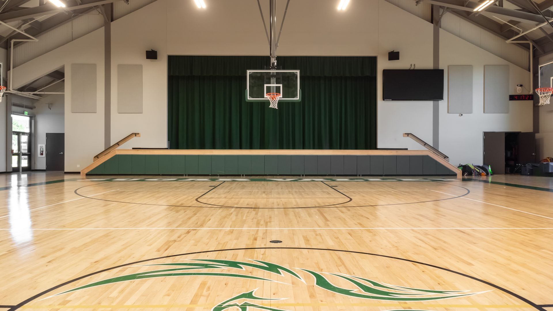 SVRCS gymnasium with a basketball hoop, stage, and polished wooden floor