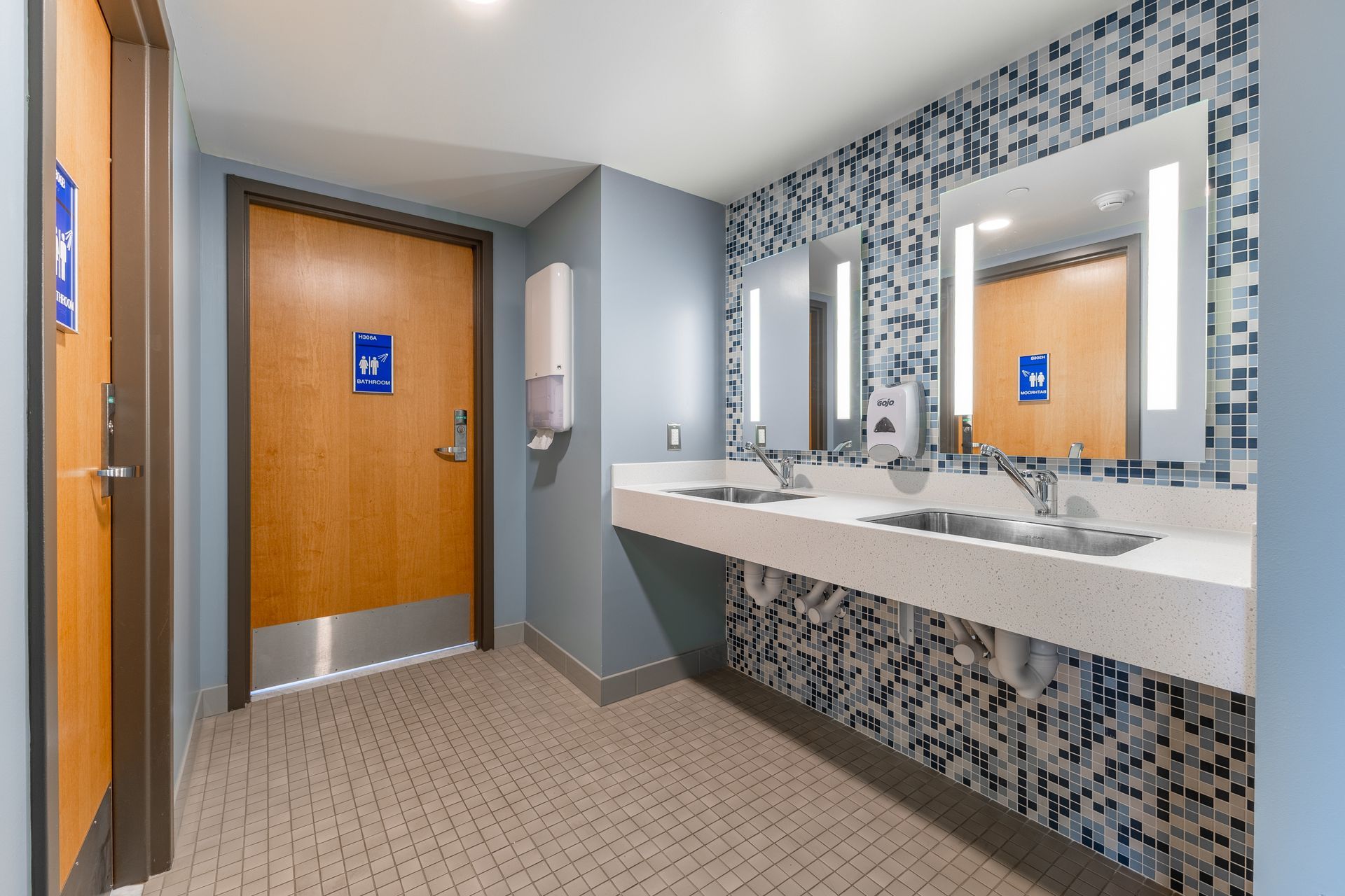 Hamilton Hall accessible bathroom with sinks, mirrors, and blue mosaic tile accents near a wooden door