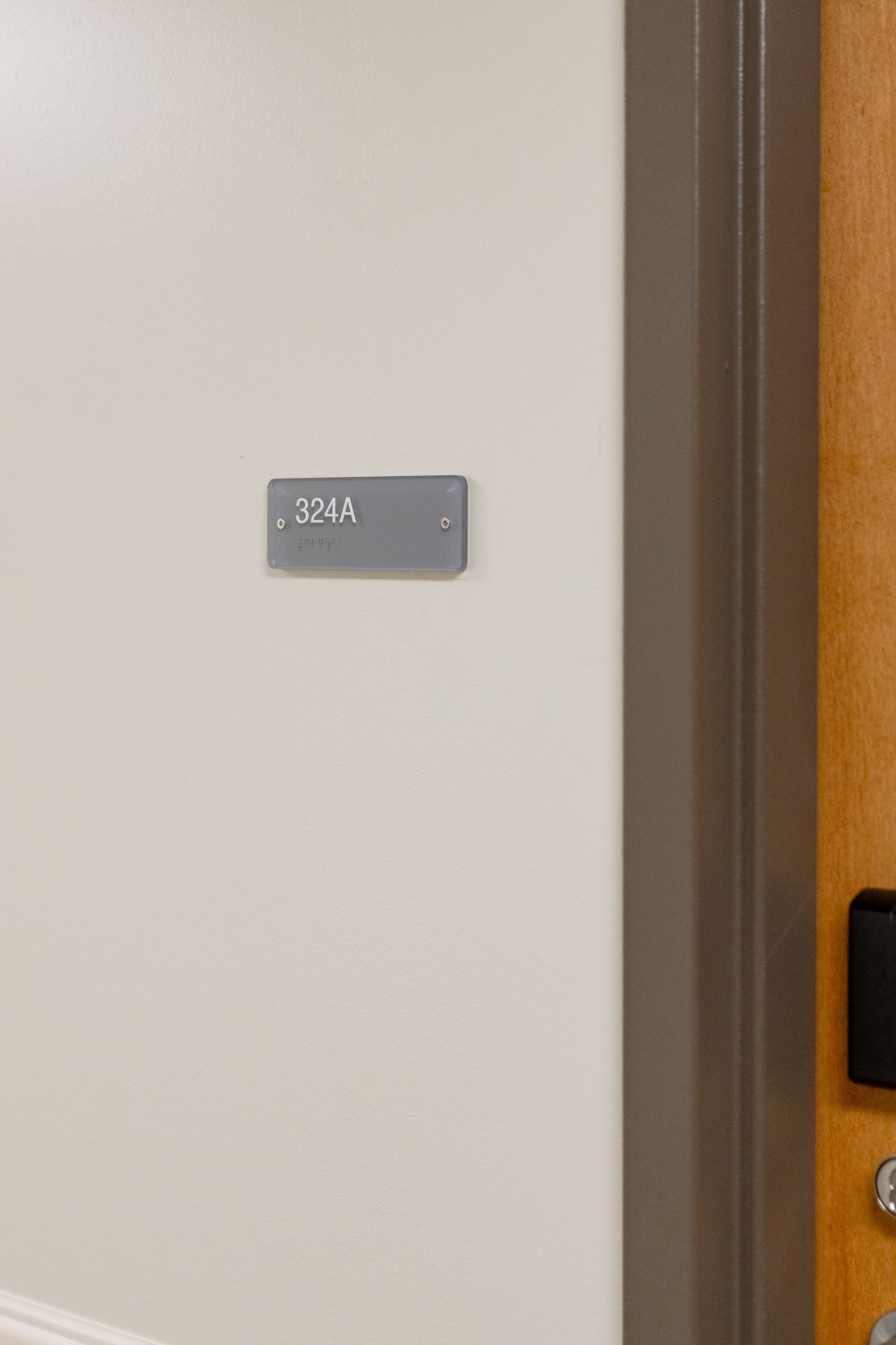 Hamilton Hall's wall sign beside a doorway on a beige hallway wall