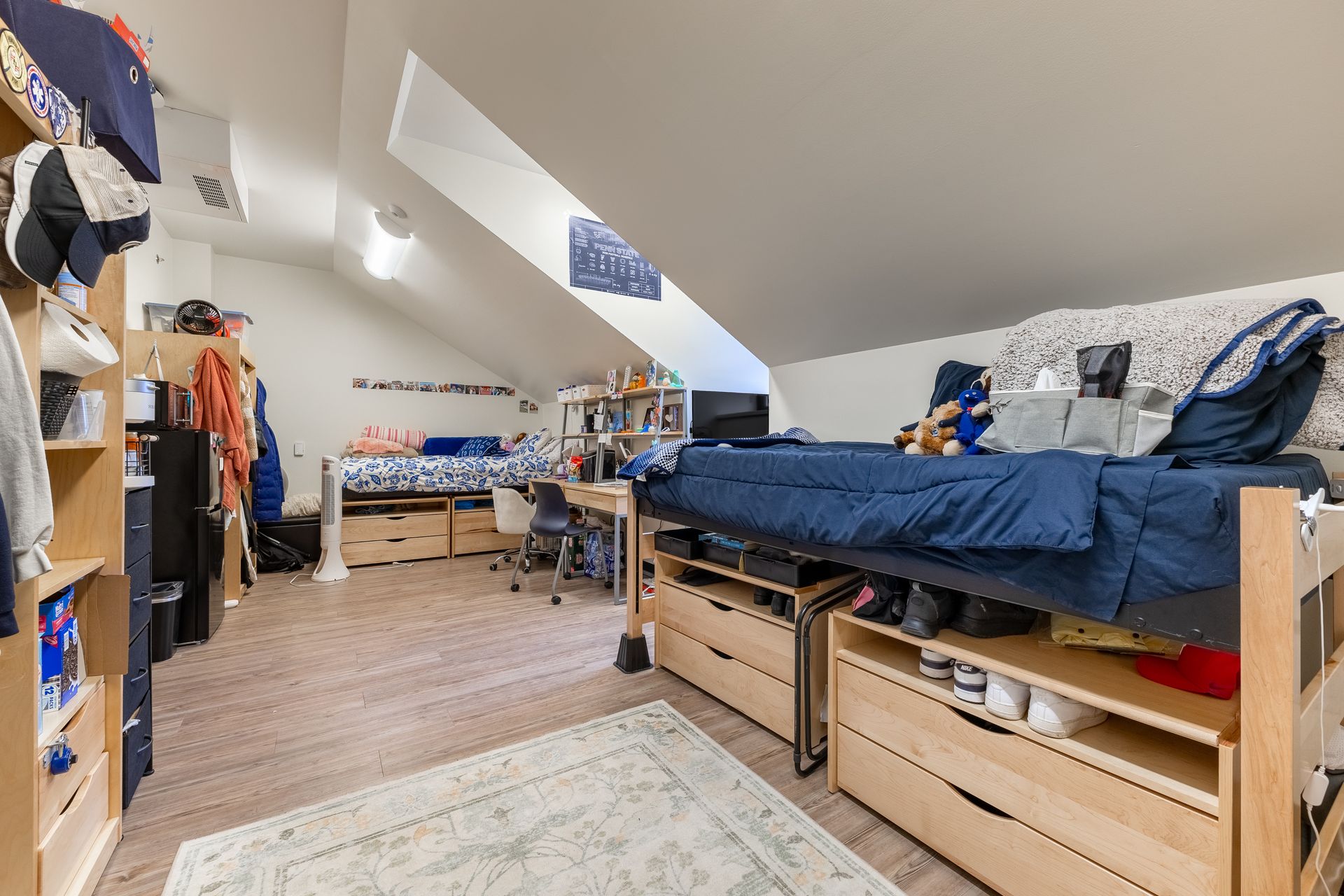 Hamilton Hall's loft bedroom with bunk beds, blue bedding, and storage drawers in a bright attic room.