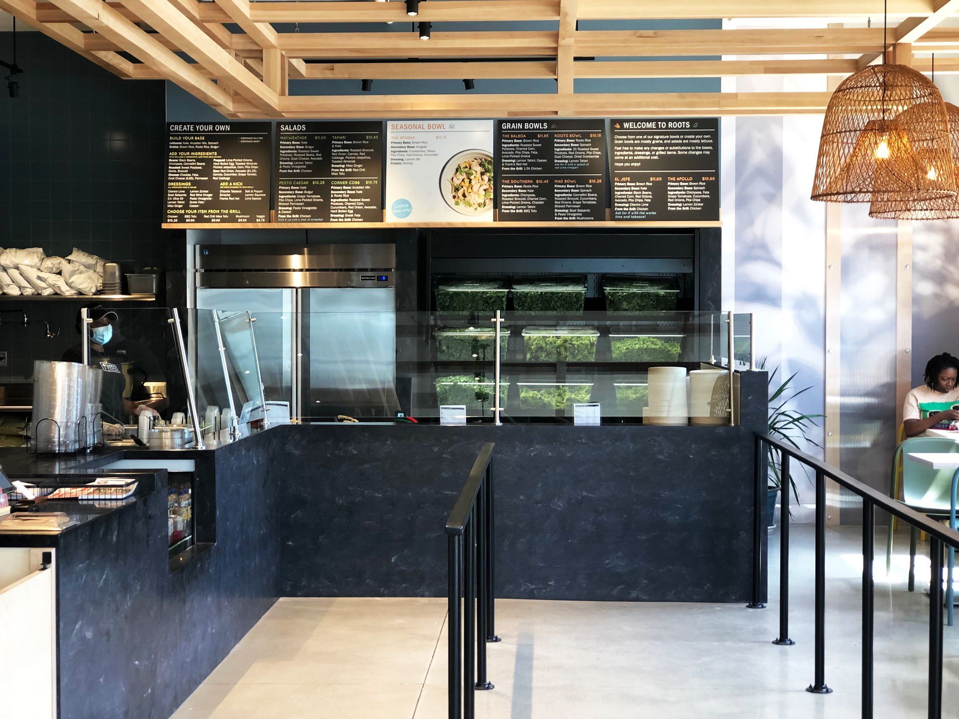 Roots Natural Kitchen interior with black counter, menu boards, and pendant lighting
