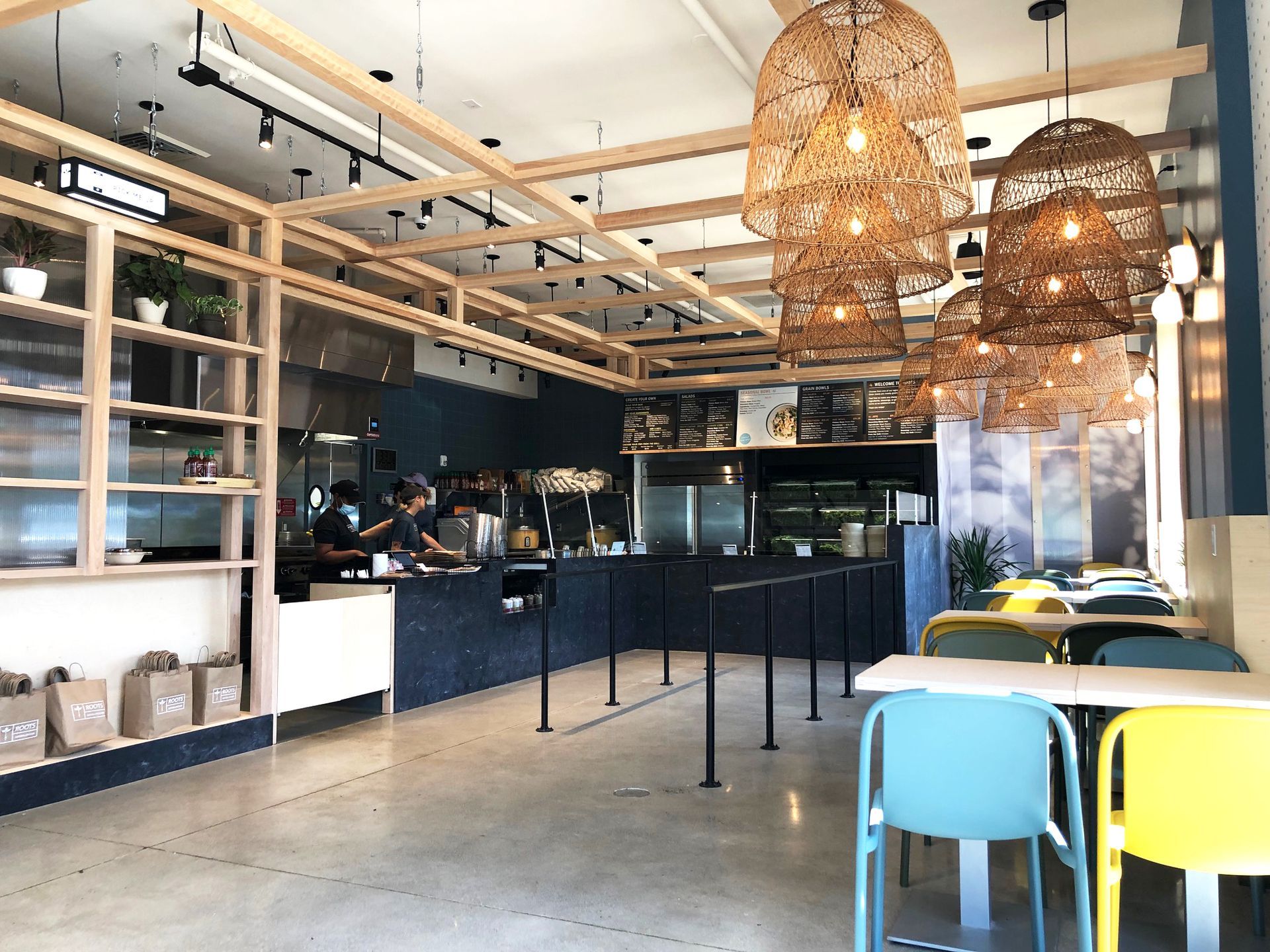 Roots Natural Kitchen interior with woven pendant lights, black counter, and colorful chairs