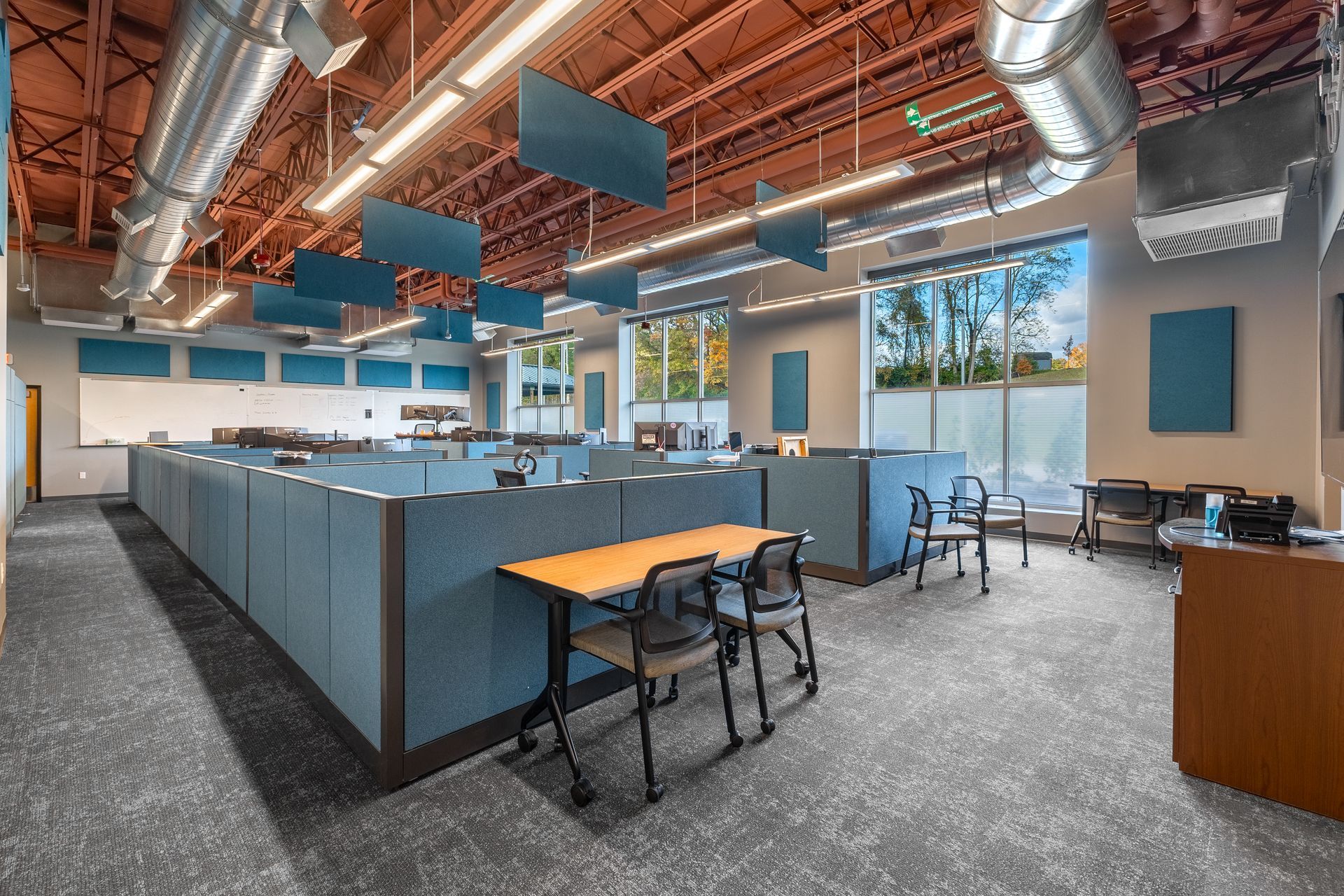 State College Area School District North Building open office with blue cubicles, desks, chairs, and exposed ceiling ducts