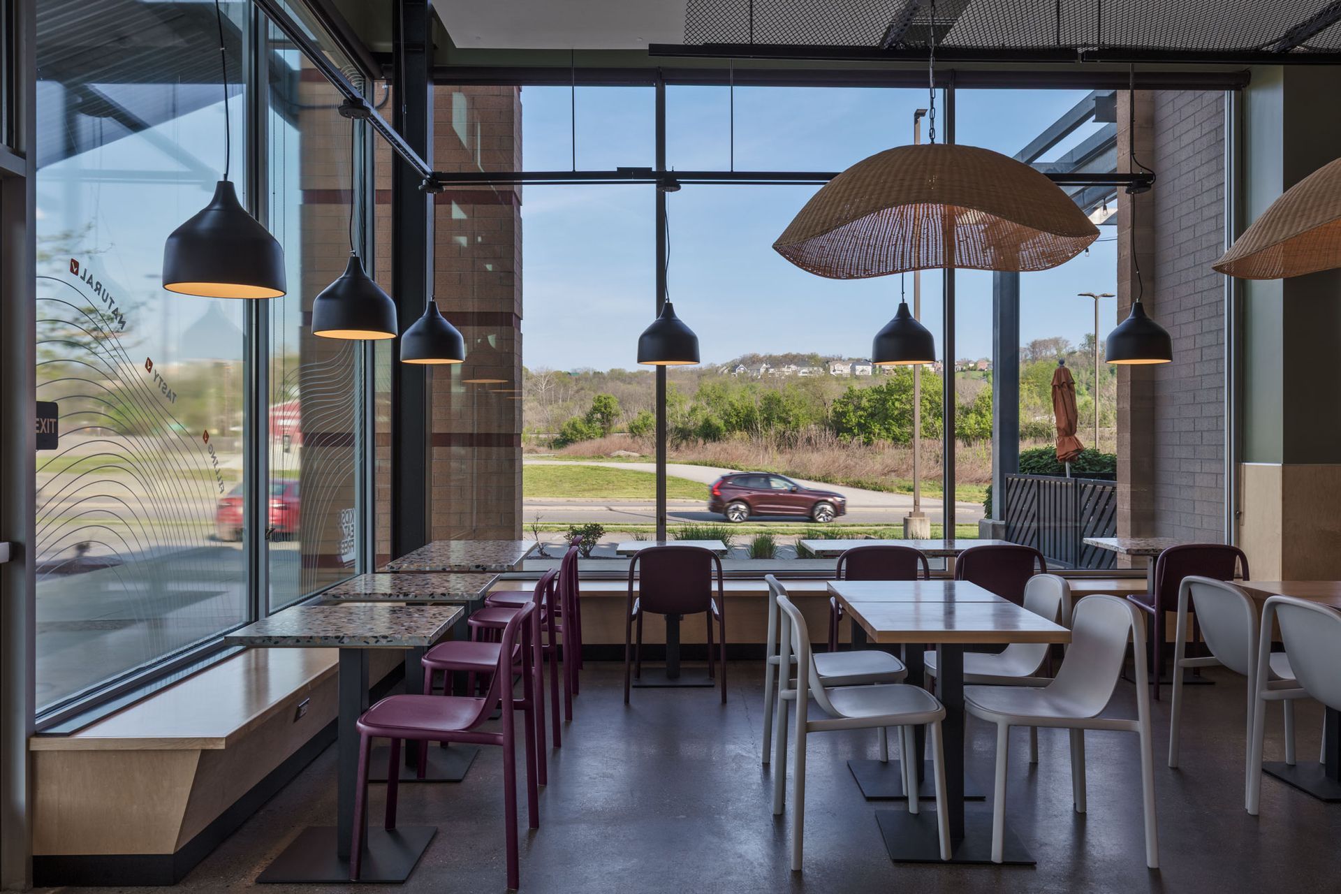 Roots Natural Kitchen's interior with tables, hanging lights, and large windows overlooking a canal and outdoor seating