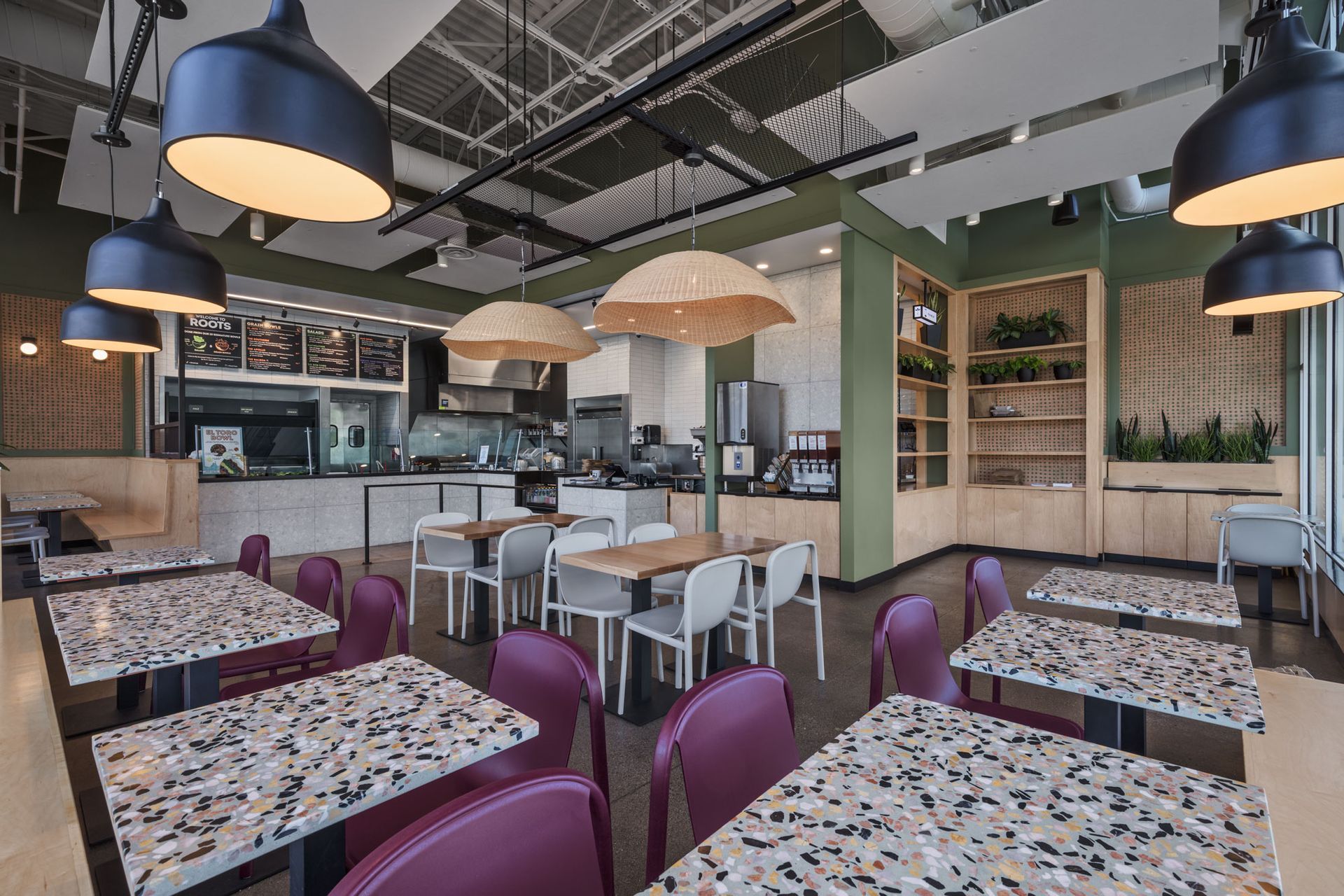 Roots Natural Kitchen's interior with patterned tables, purple chairs, hanging lamps, and a counter area