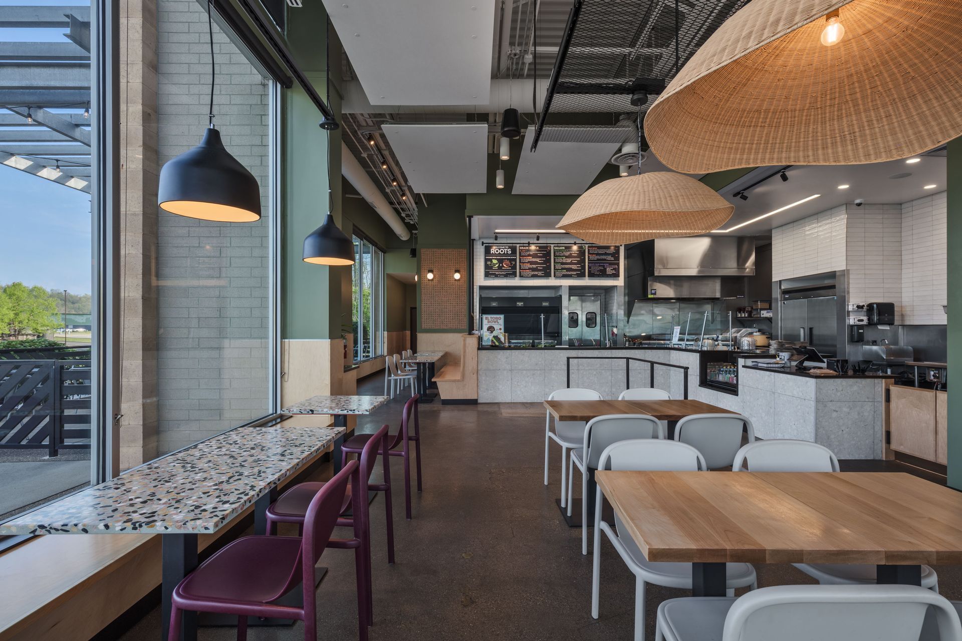 Roots Natural Kitchen's interior with wooden tables, hanging pendant lights, and a long counter seating area