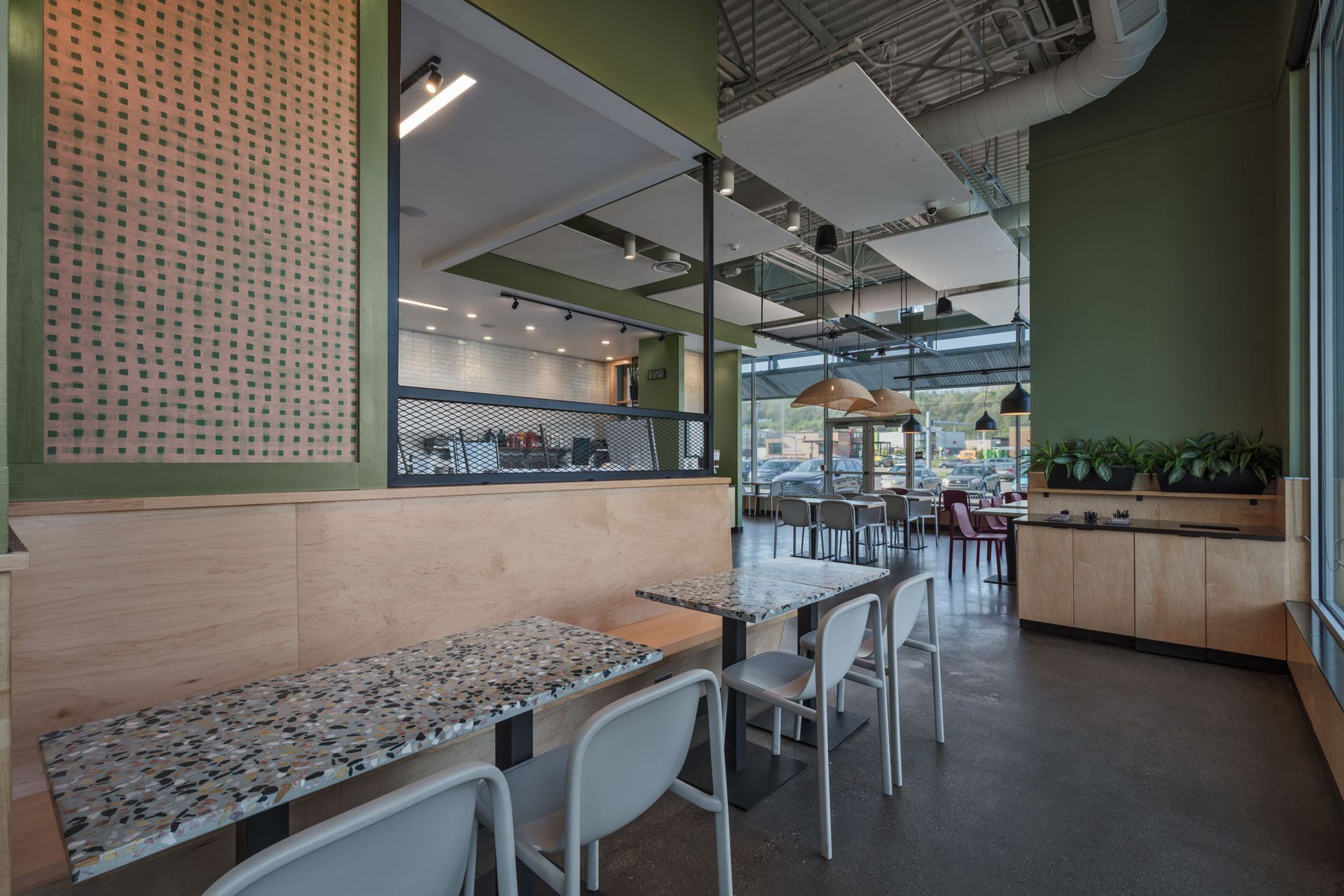Roots Natural Kitchen's interior with terrazzo tables, white chairs, and hanging lights