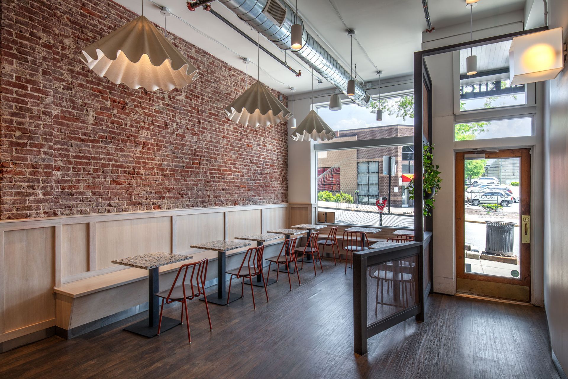 Roots Natural Kitchen's interior with brick walls, wooden tables, and sunlight by the front windows.