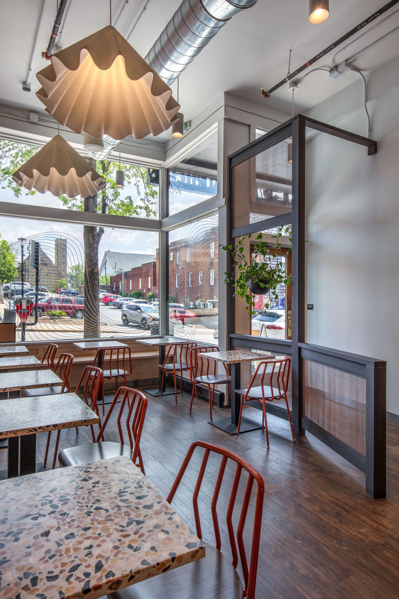 Roots Natural Kitchen's interior with wooden tables, chairs, hanging lights, and large windows overlooking the street