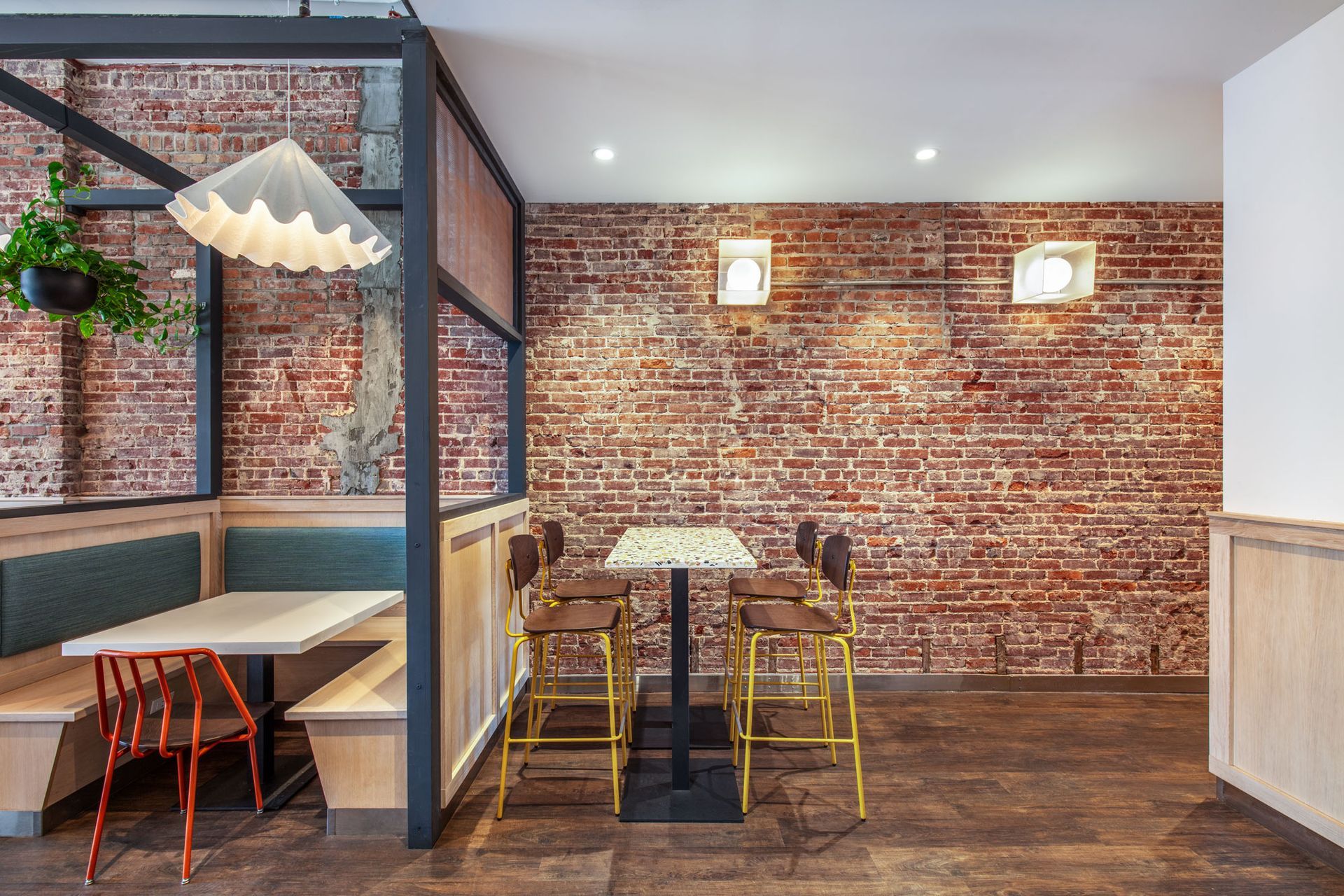 Roots Natural Kitchen's interior with brick wall, booth seating, small table, and hanging lights
