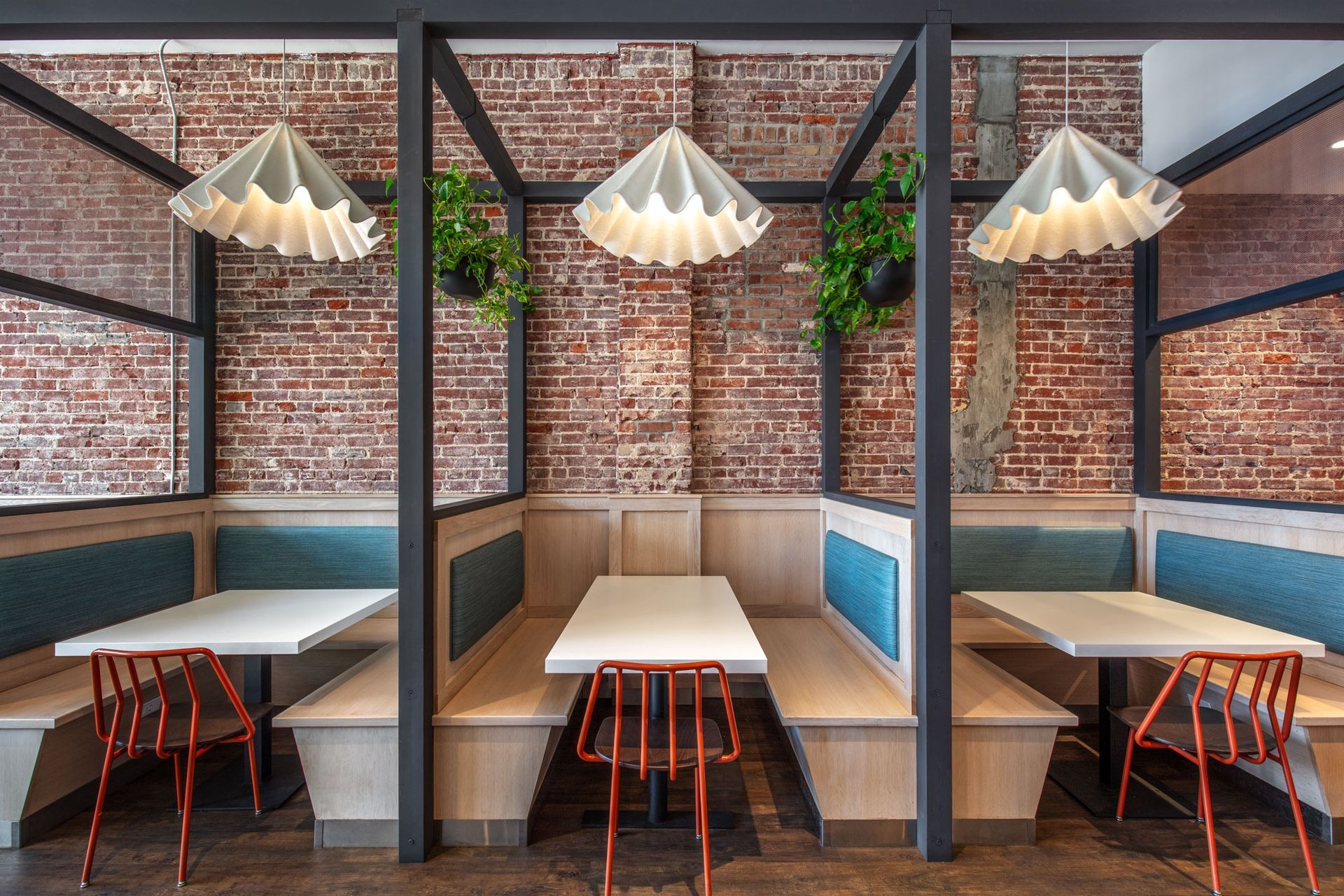 Roots Natural Kitchen's interior booths with brick walls, hanging pendant lights, and white tables in a row