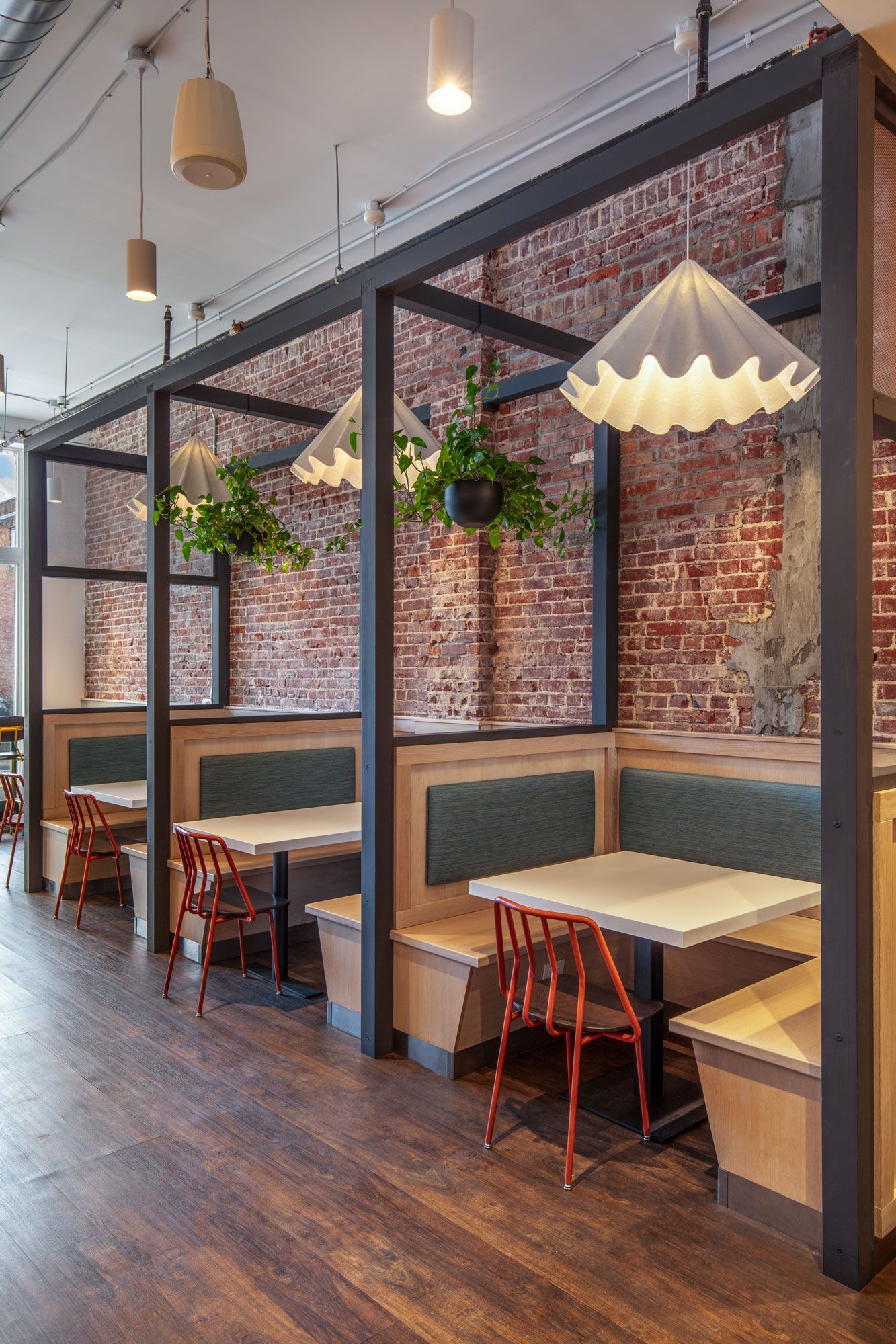 Roots Natural Kitchen's interior seating with booths, wooden tables, hanging plants, and exposed brick walls