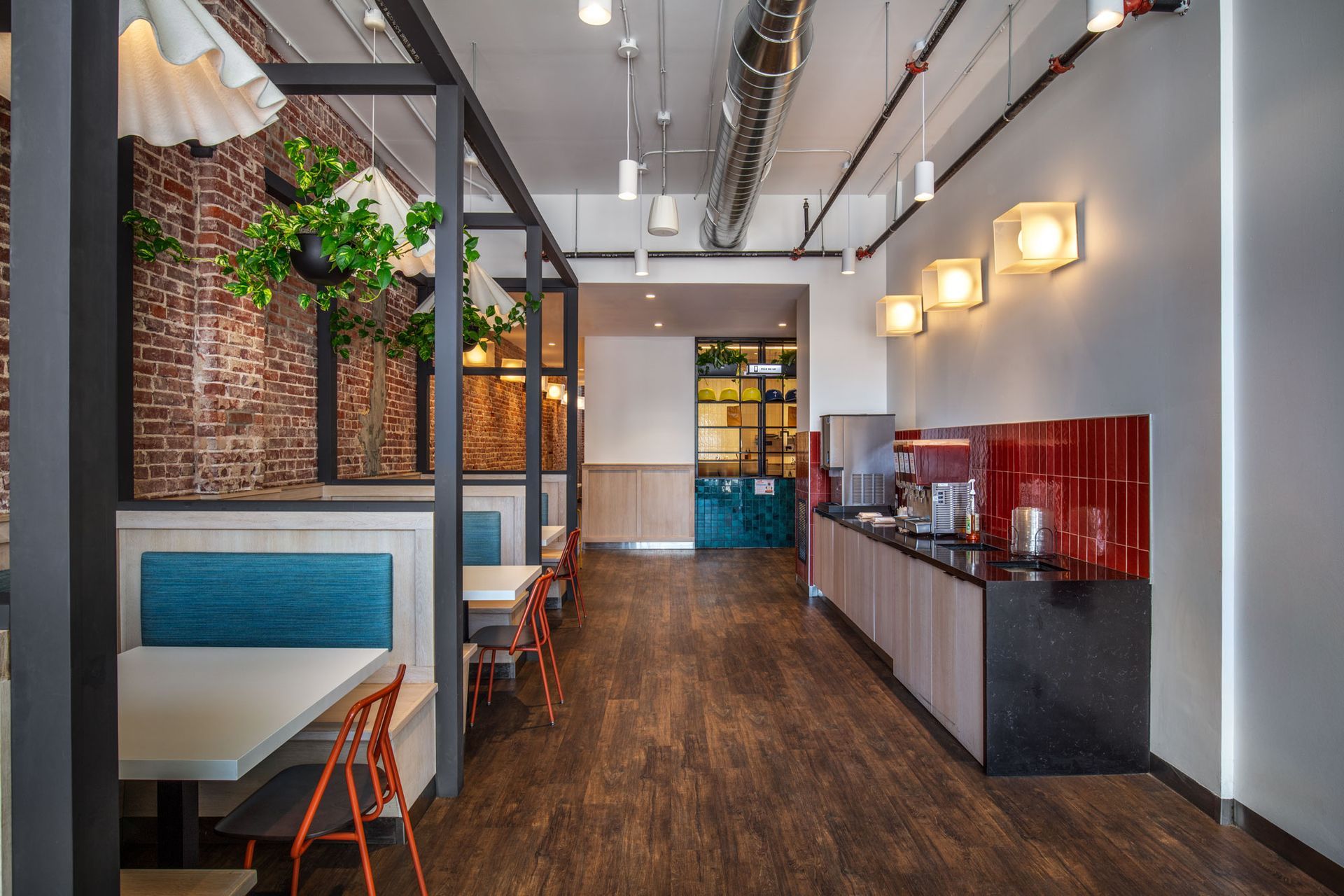 Roots Natural Kitchen's interior with brick wall, blue booths, wooden tables, and pendant lights