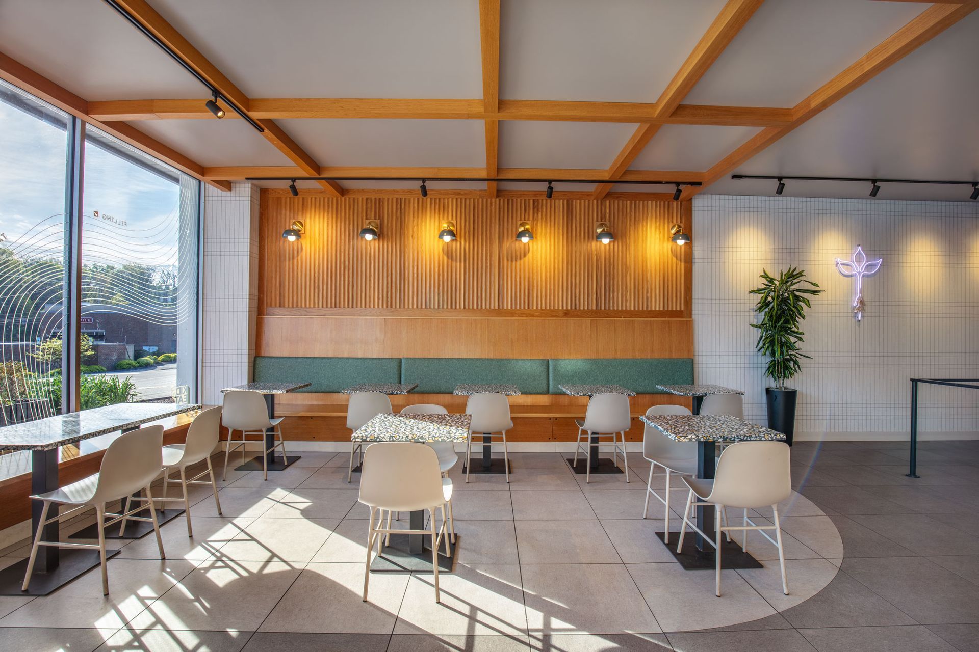Roots Natural Kitchen's interior lounge with wooden beams, large windows, and tables and chairs in warm sunlight