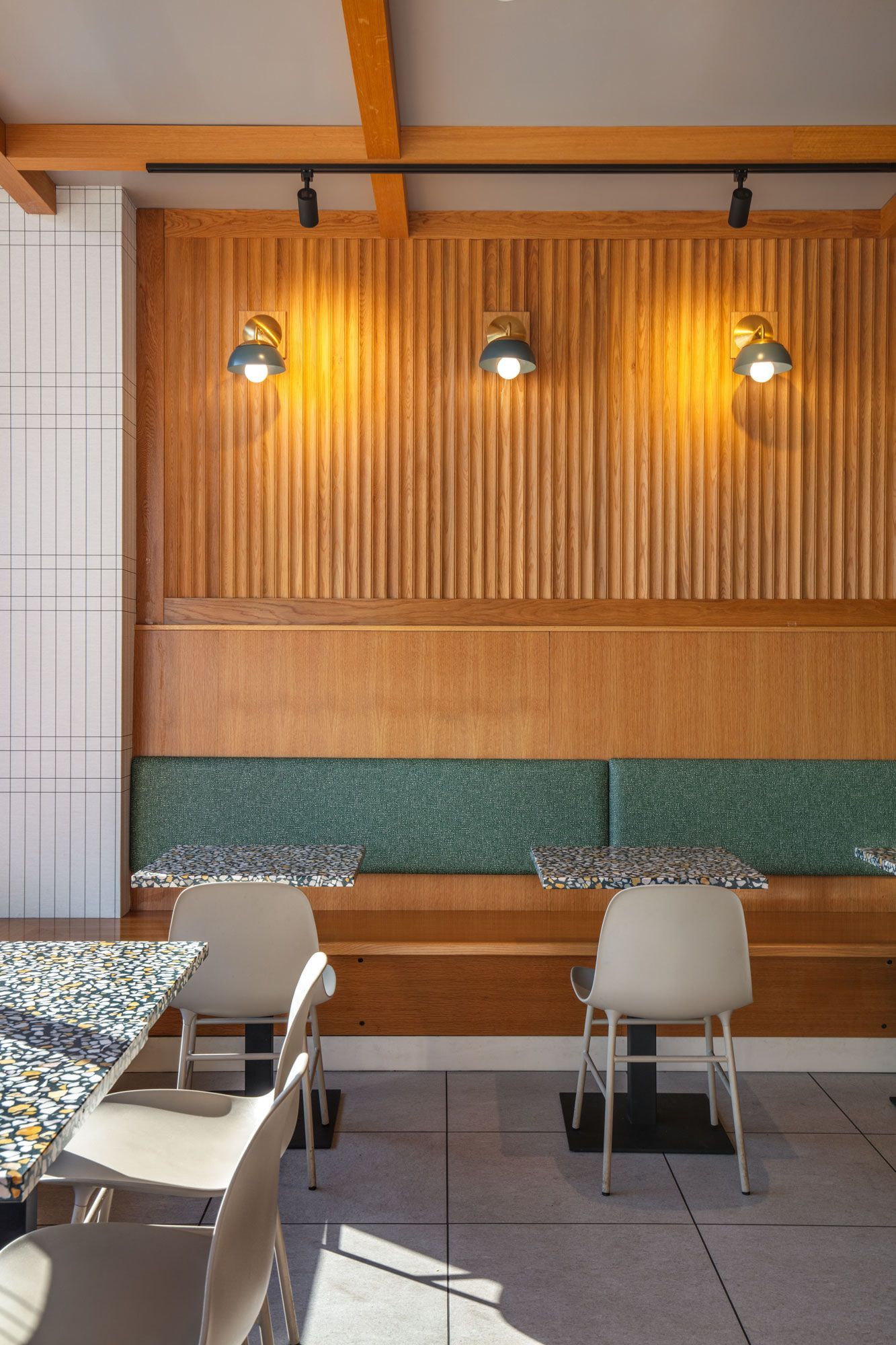 Roots Natural Kitchen's interior with wooden wall, hanging lights, and empty chairs and tables