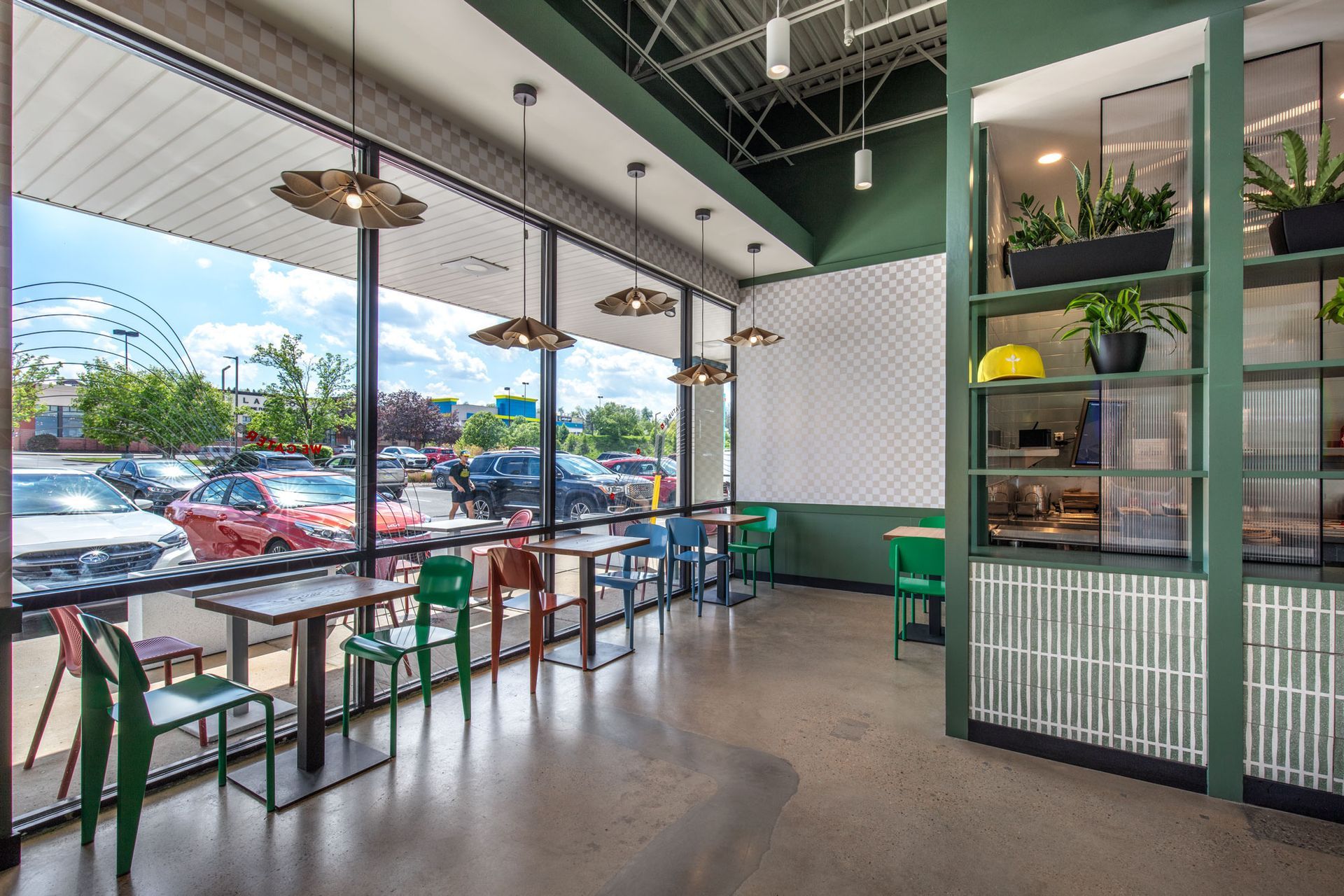 Roots Natural Kitchen interior with large windows, green accents, and tables by the glass wall
