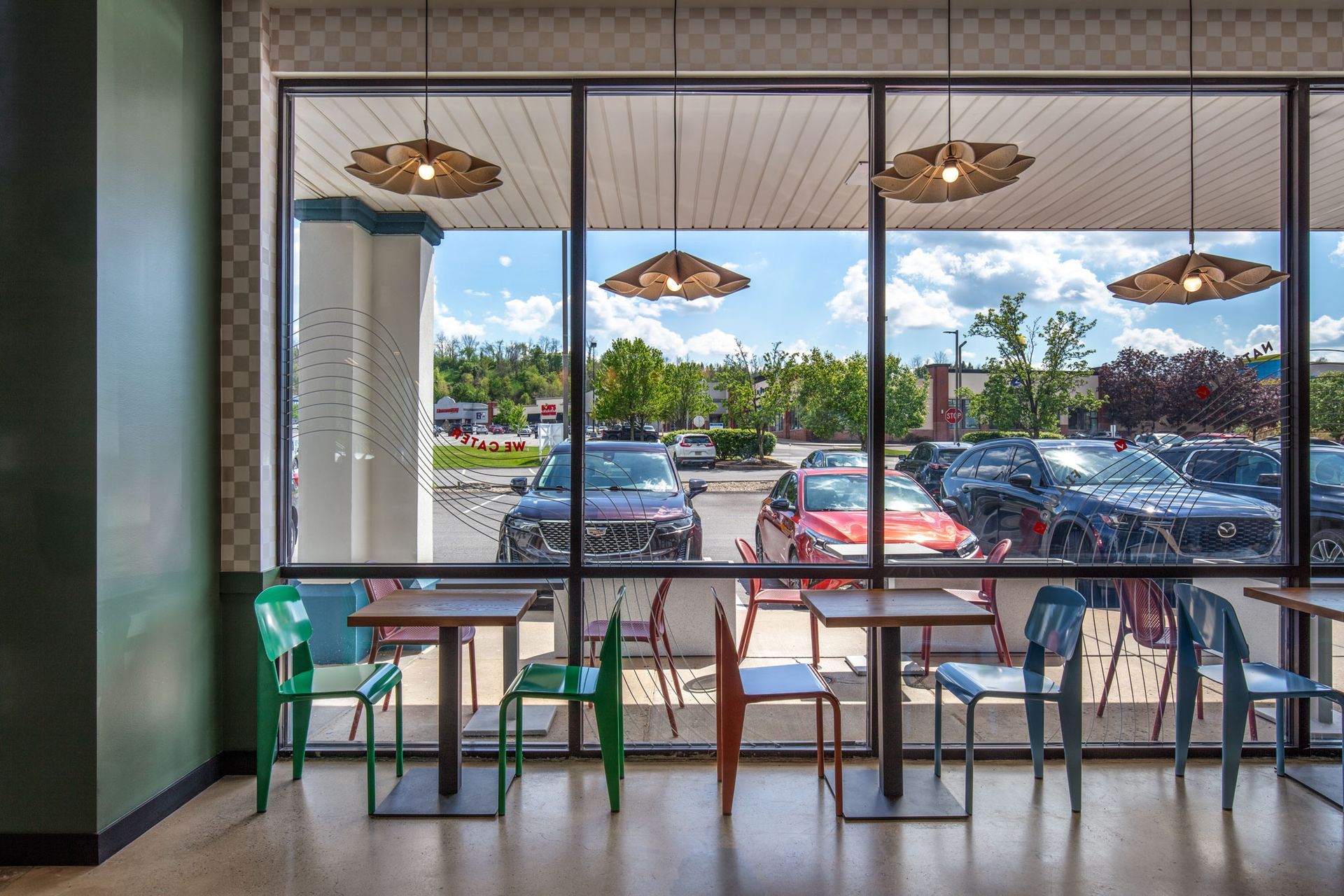 Roots Natural Kitchen's interior seating by a large window overlooking a sunny parking lot