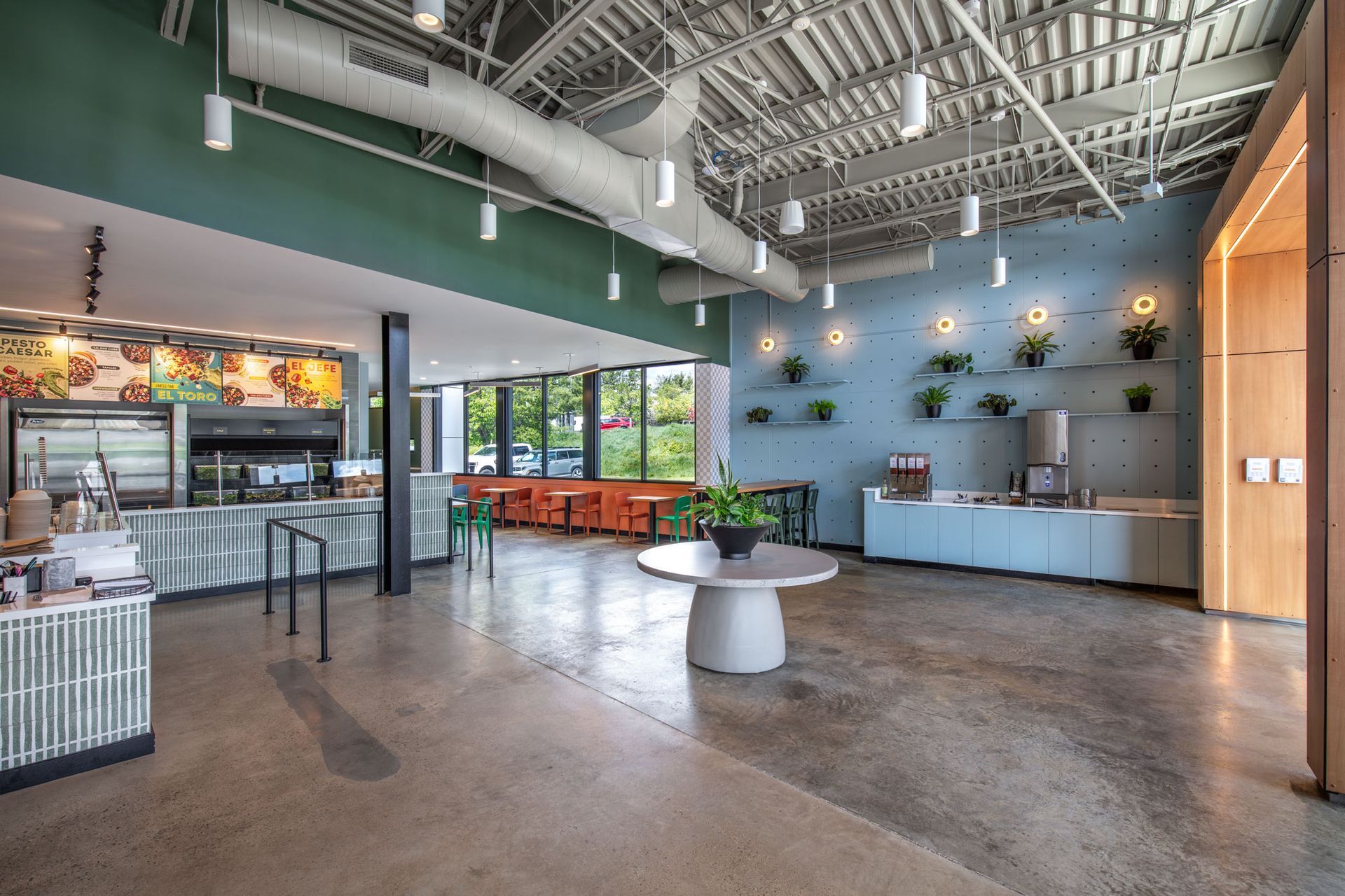 Roots Natural Kitchen's interior with high ceilings, tables, counter seating, and large windows