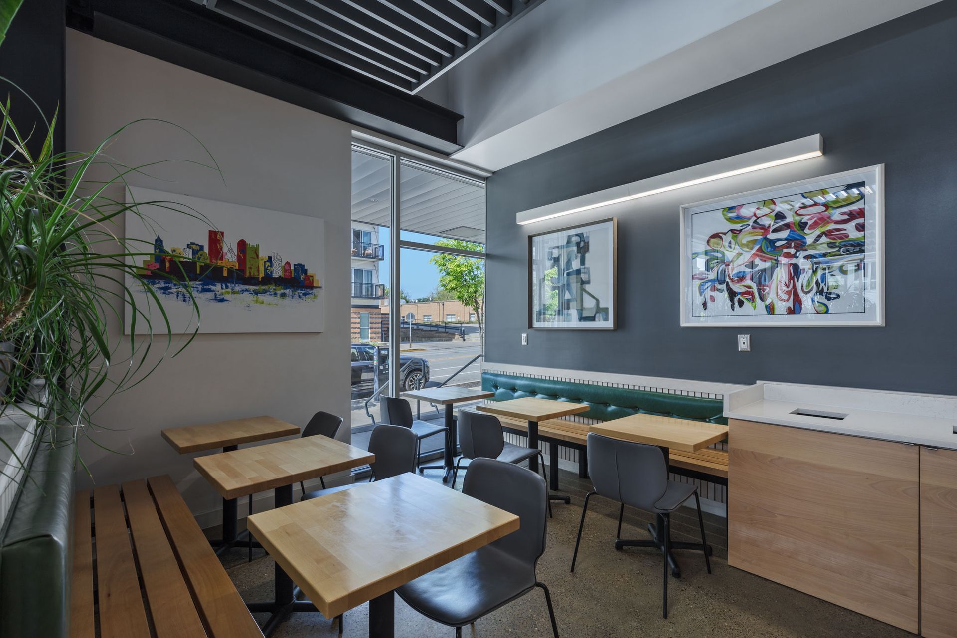 Roots Natural Kitchen's interior with wooden tables, chairs, wall art, and large windows overlooking a street.