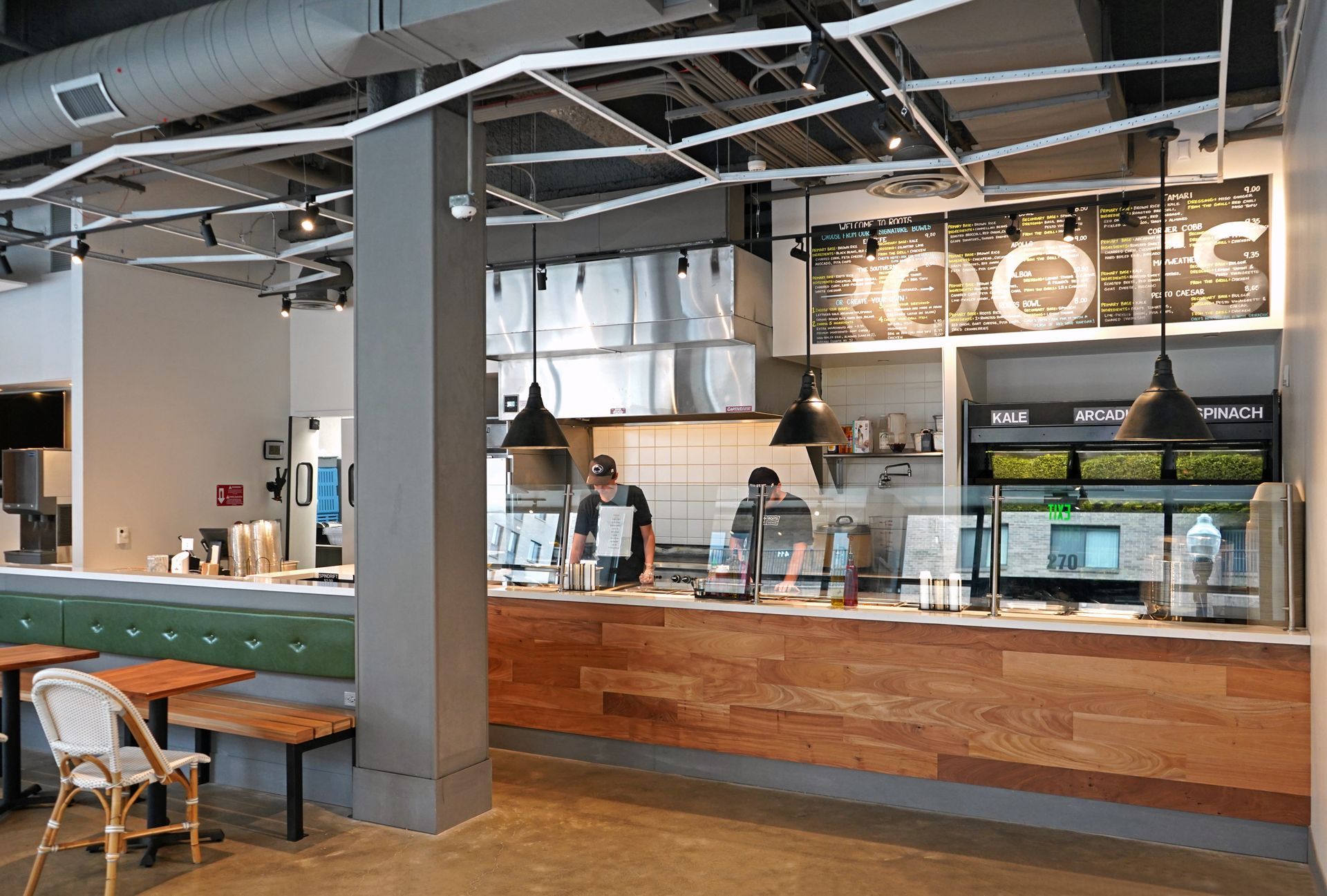 Roots Natural Kitchen's counter with staff, wood paneling, hanging lights, and a small seating area