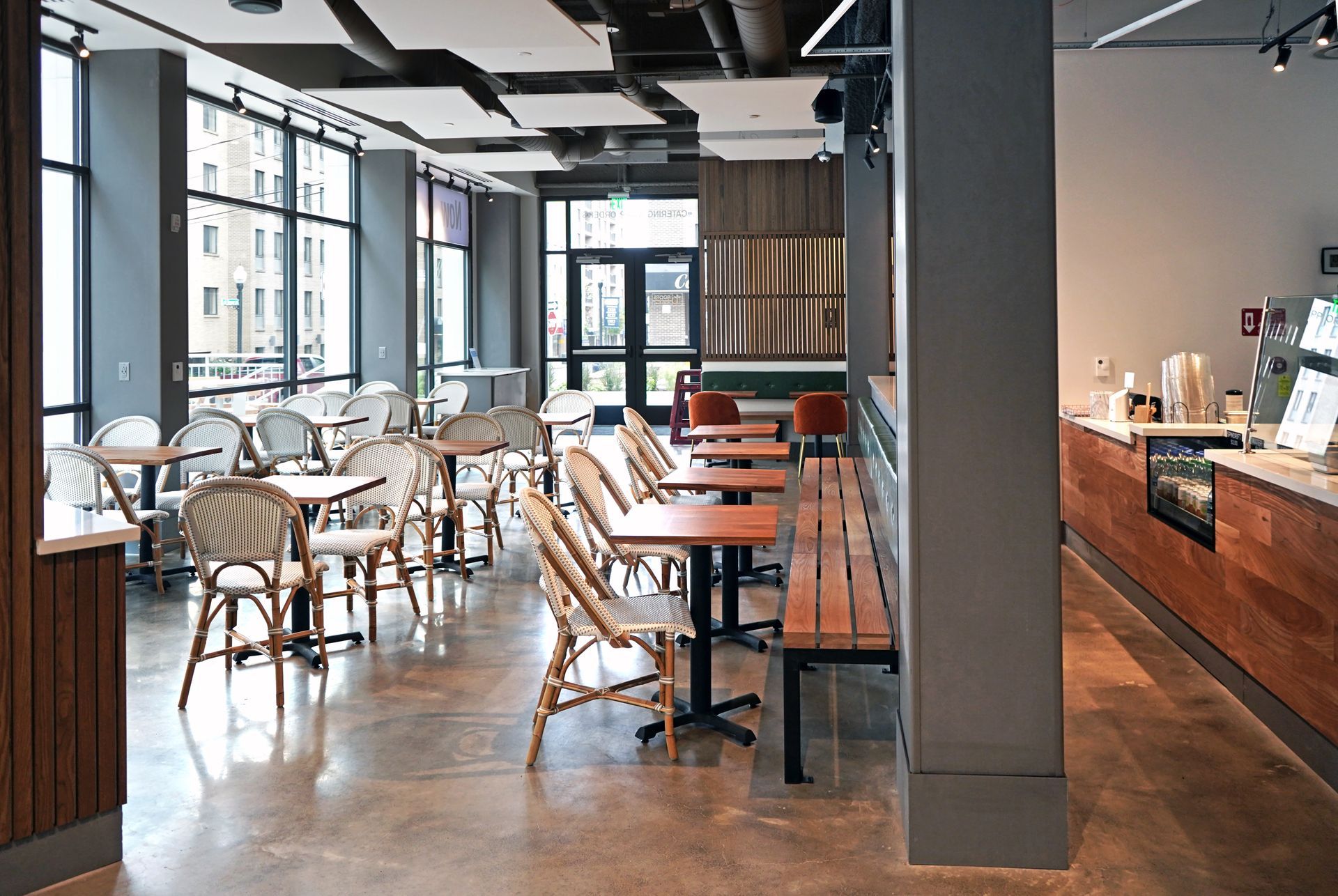 Roots Natural Kitchen interior with tables, chairs, and a long wooden counter beside a tall pillar and window wall.