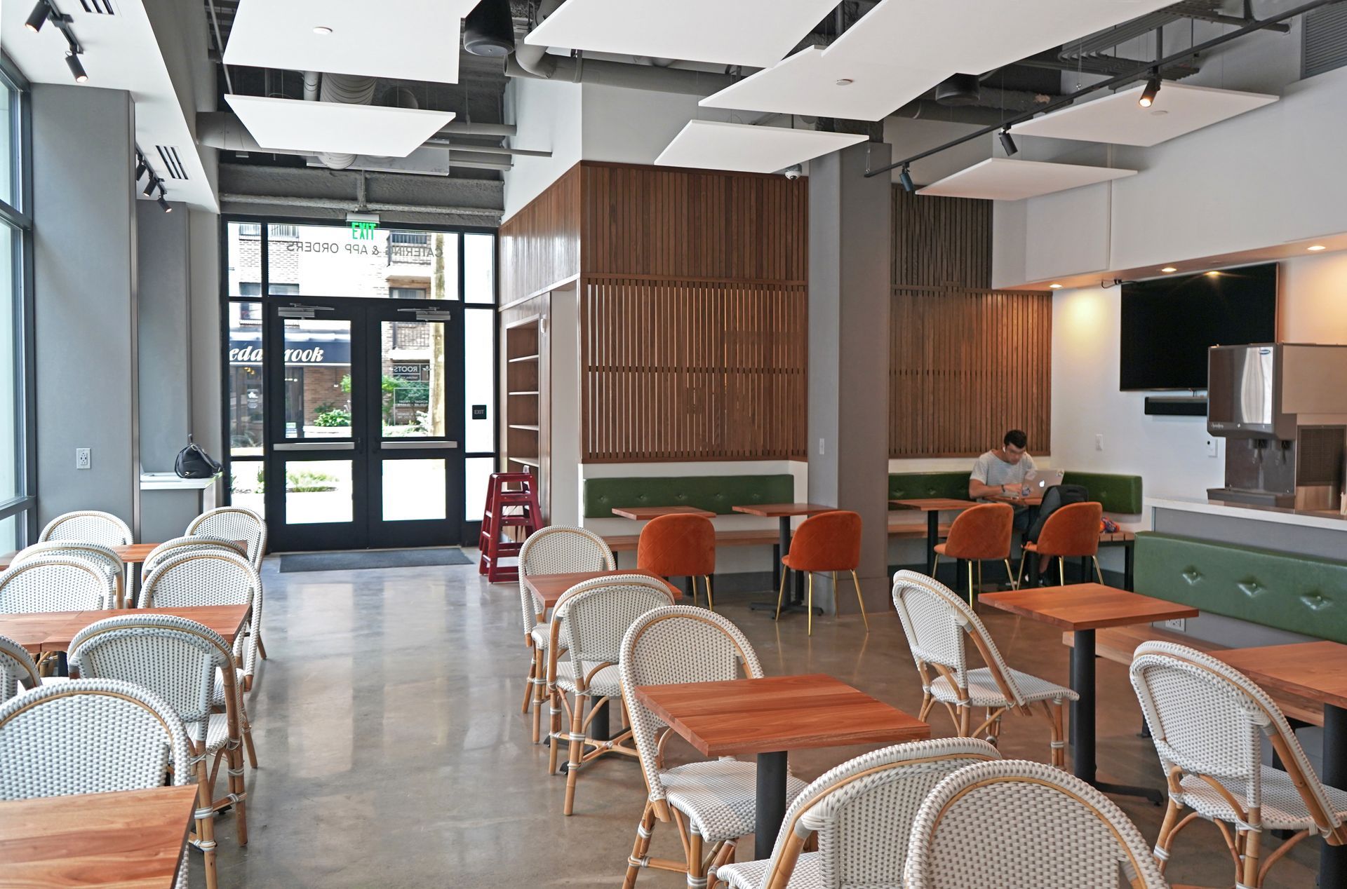 Roots Natural Kitchen's interior with wicker chairs, wooden tables, and a service counter.