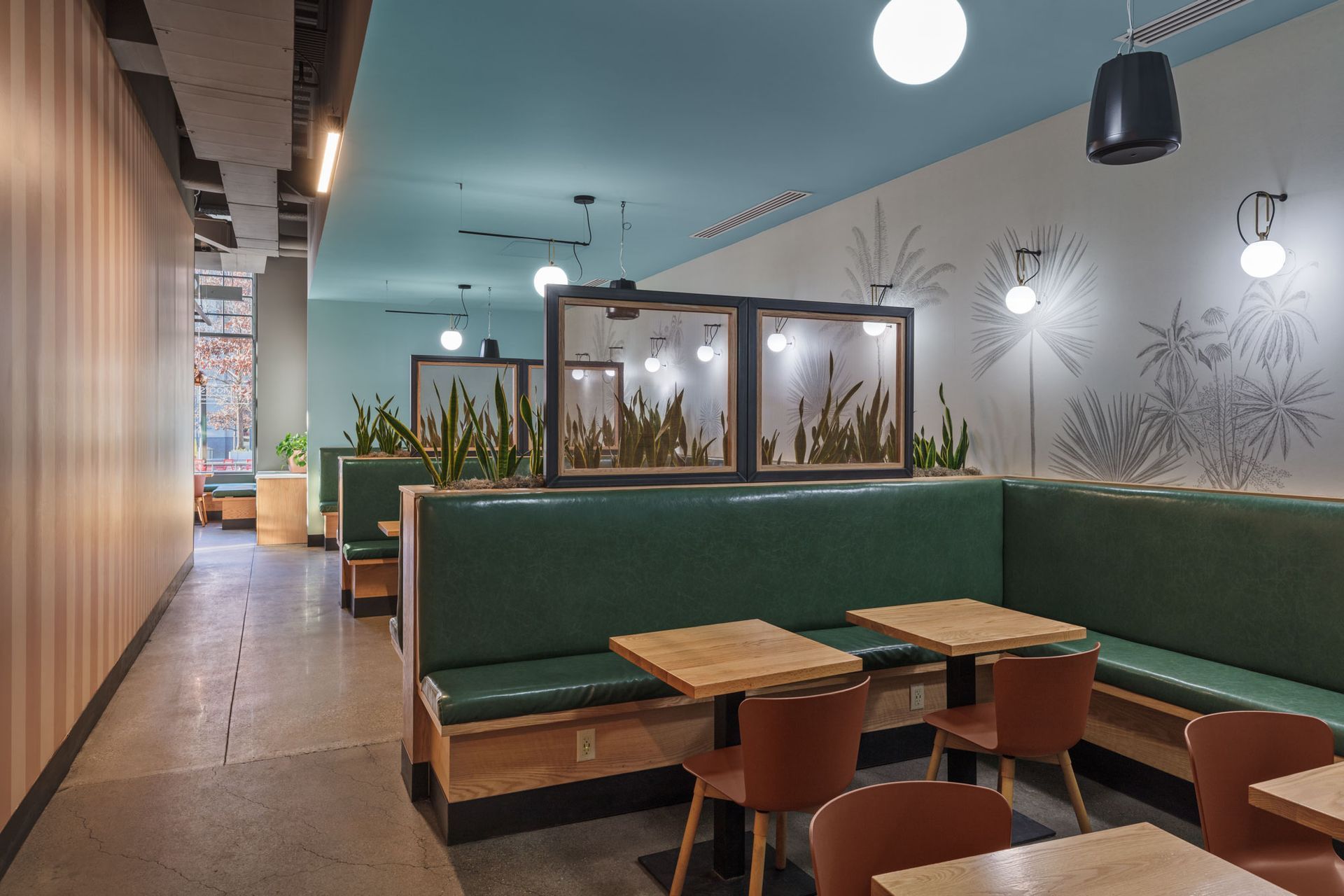Roots Natural Kitchen booth seating with green benches, wooden tables, and warm hanging lights
