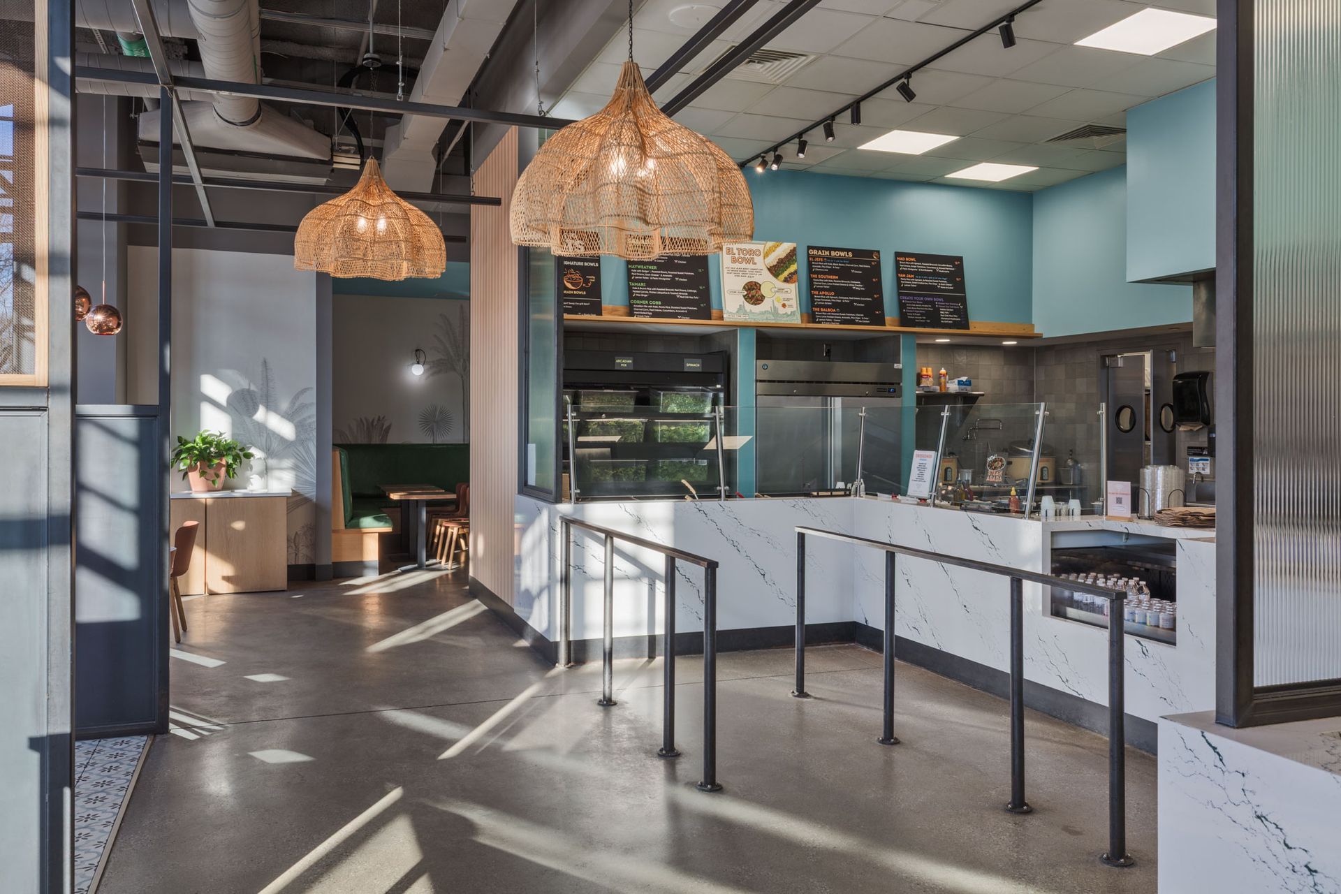 Roots Natural Kitchen's counter with pendant lights, menu boards, and sunlight streaming across the empty seating area