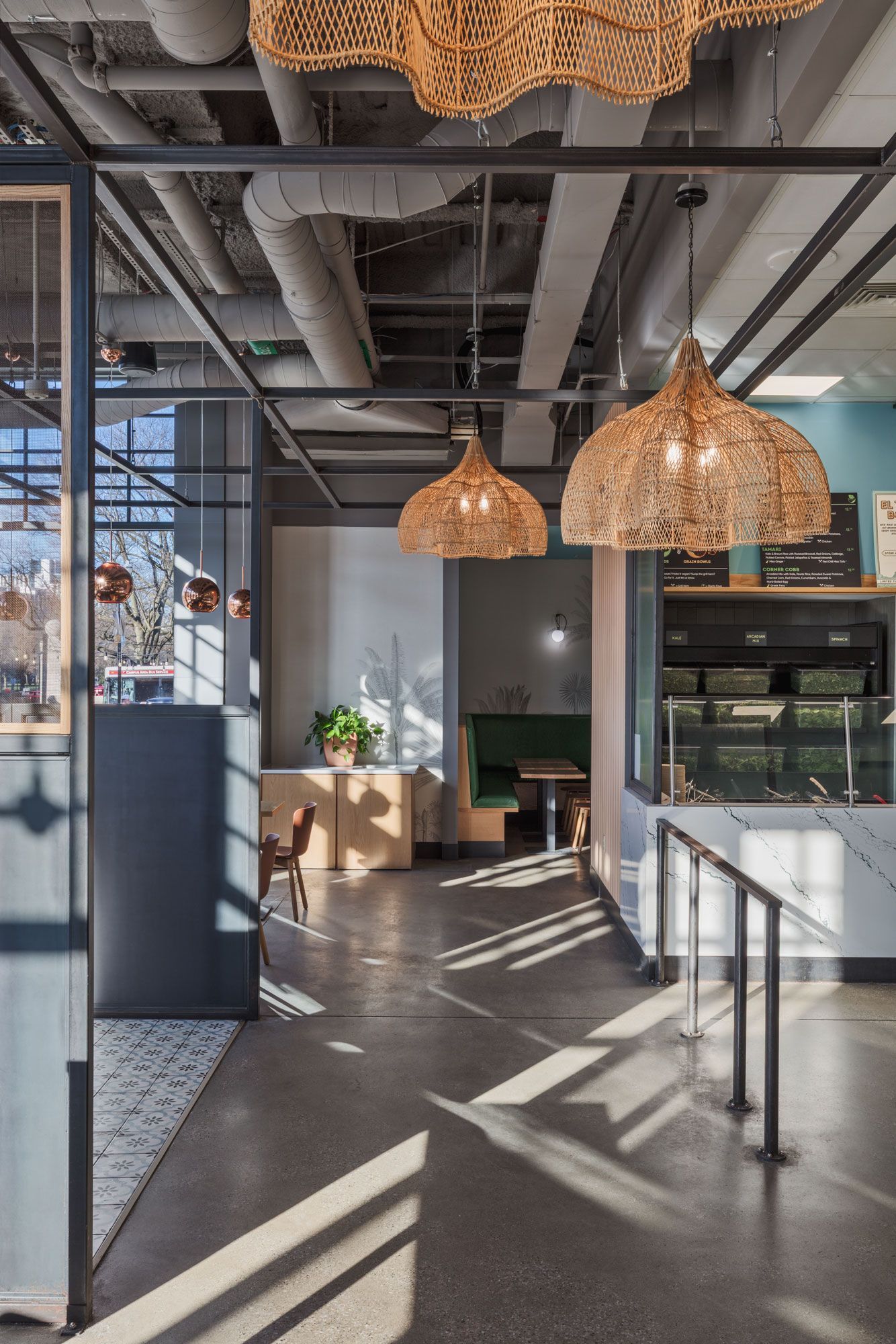 Roots Natural Kitchen's interior with woven pendant lights, long shadows, and a counter near large windows