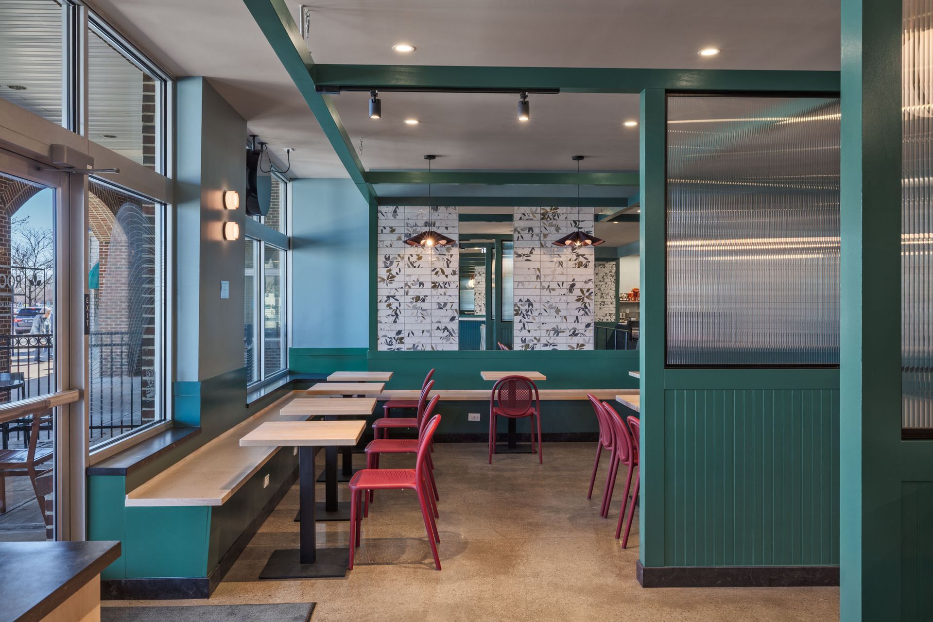 Roots Natural Kitchen's interior with red chairs, long tables, and large windows