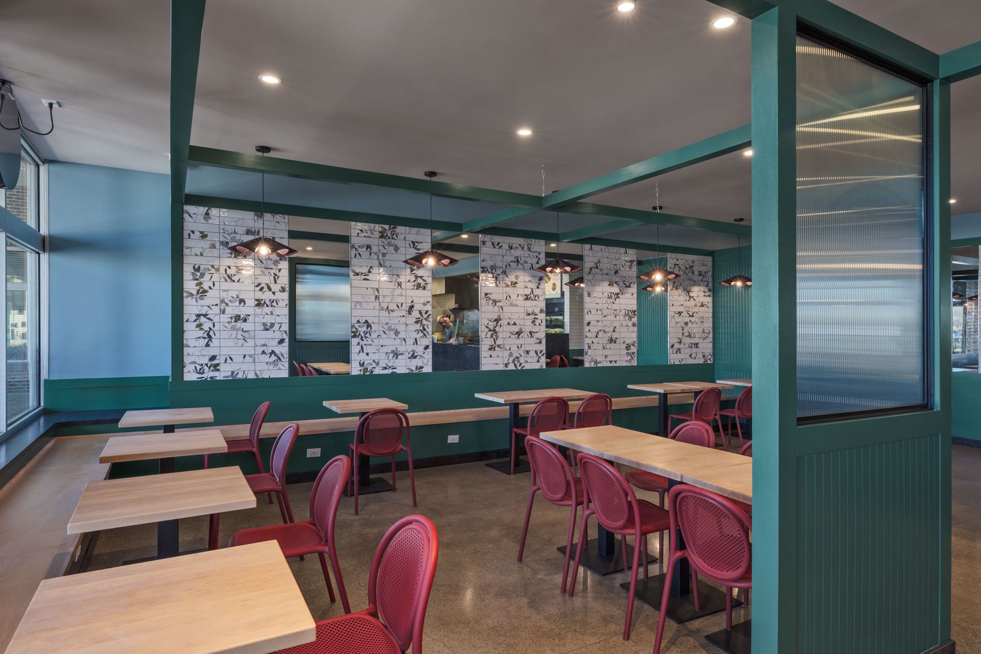 Roots Natural Kitchen's dining area with teal walls, red chairs, and patterned booth seating