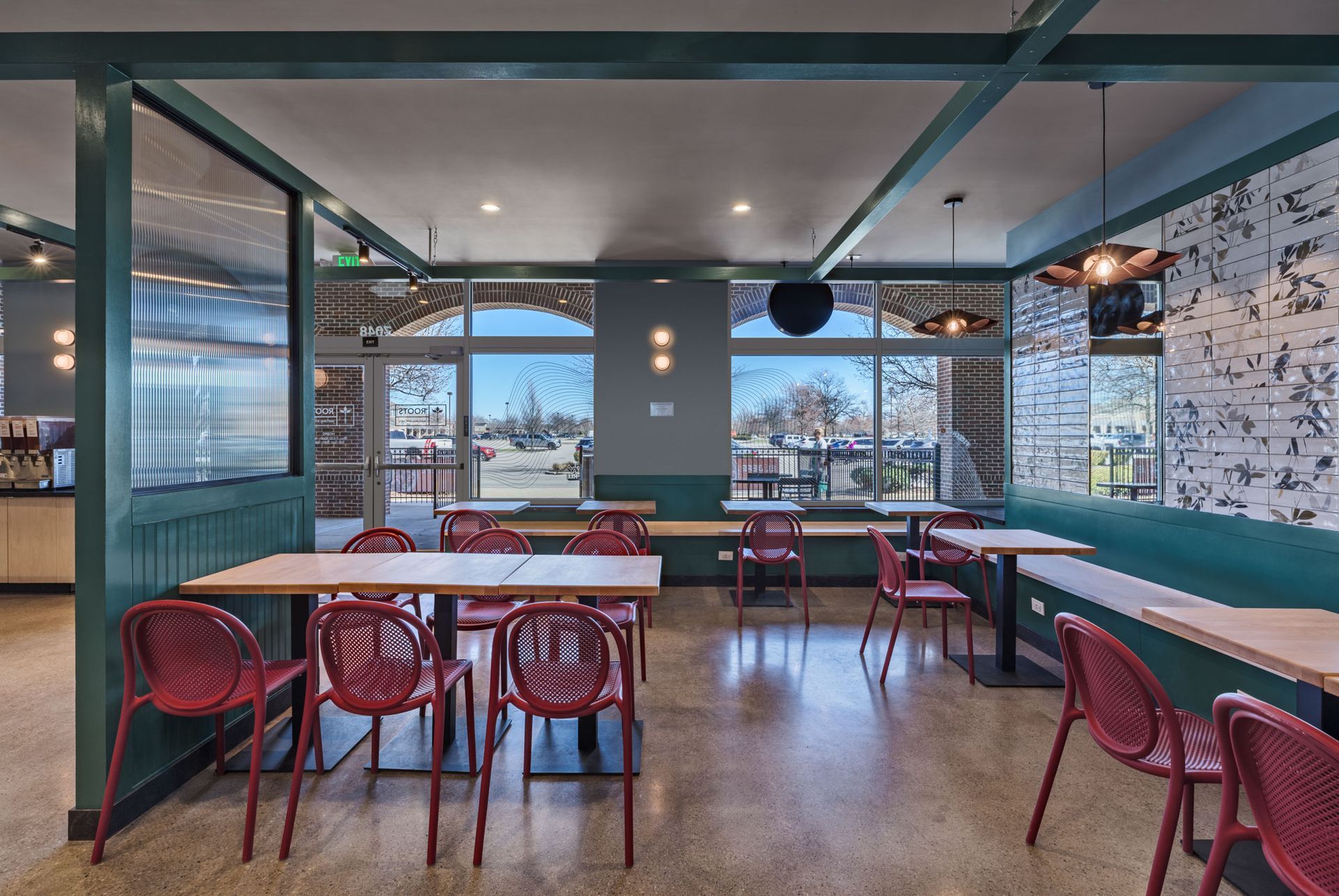 Roots Natural Kitchen's interior with red chairs, wooden tables, and large windows overlooking water