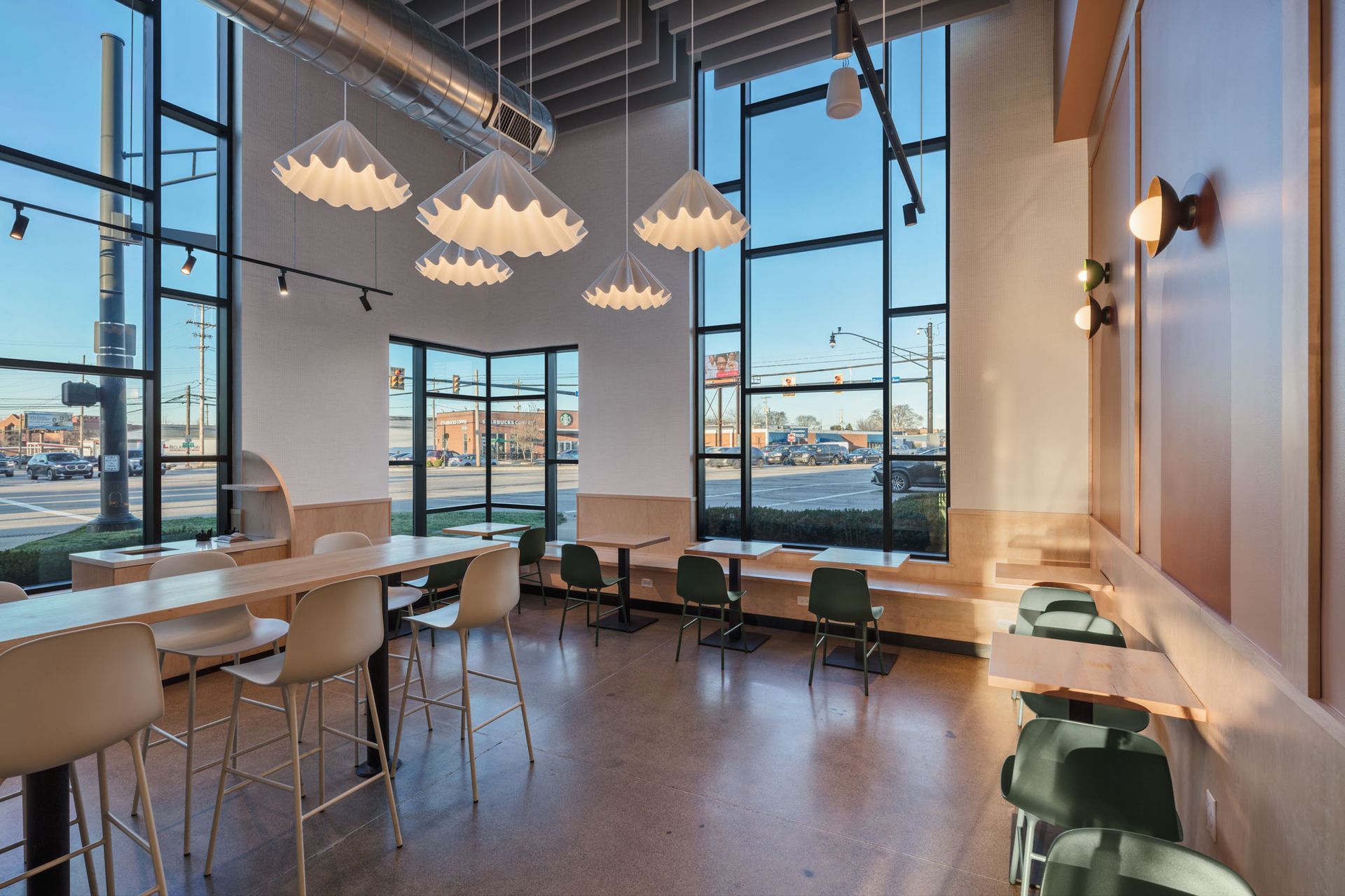 Roots Natural Kitchen's lounge with large windows, pendant lights, and tables overlooking a city view