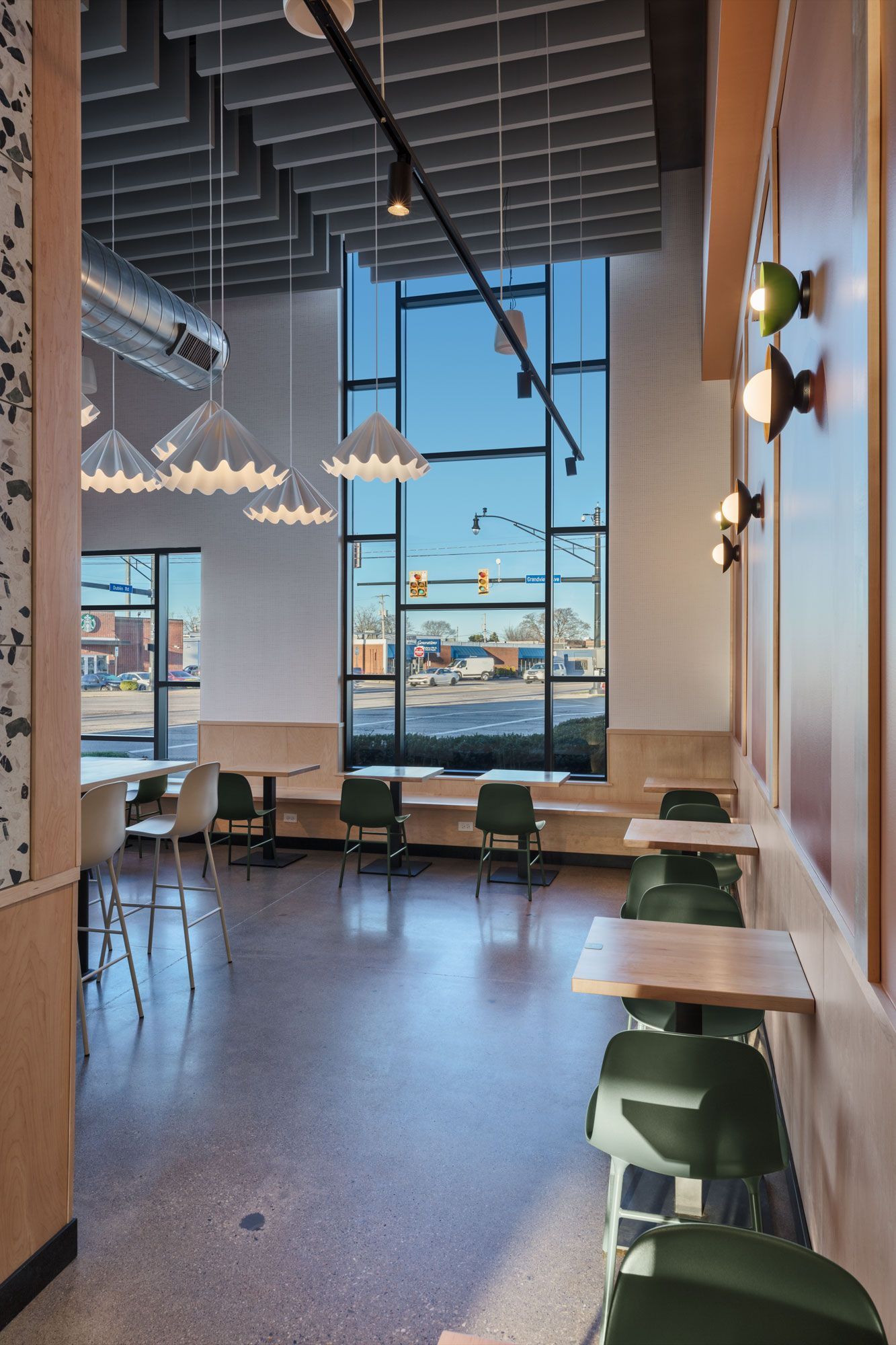 Roots Natural Kitchen's interior with large windows, pendant lights, and green chairs overlooking the waterfront