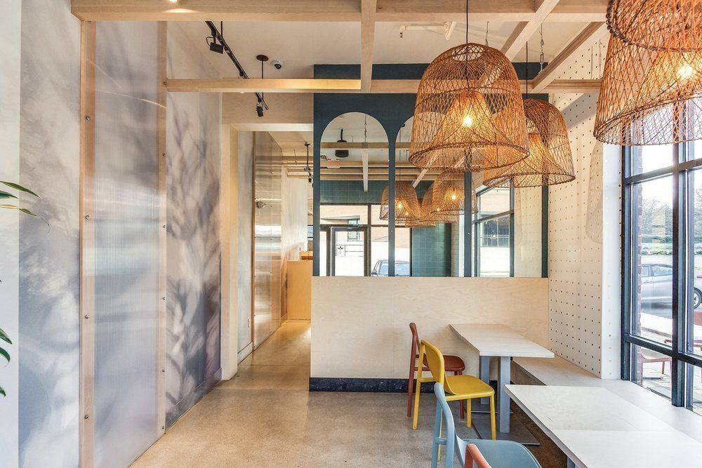 Roots Natural Kitchen with woven pendant lights, wooden tables, and large windows overlooking the street