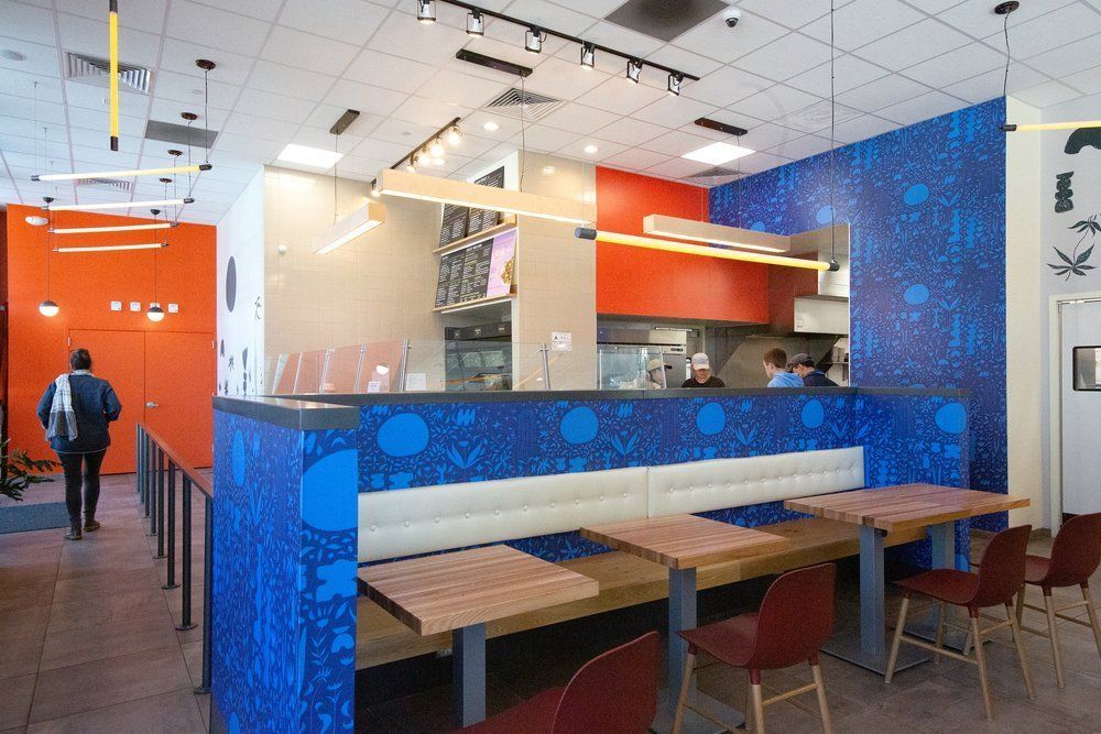 Roots Natural Kitchen's interior with blue booth seating, red accents, and a counter area
