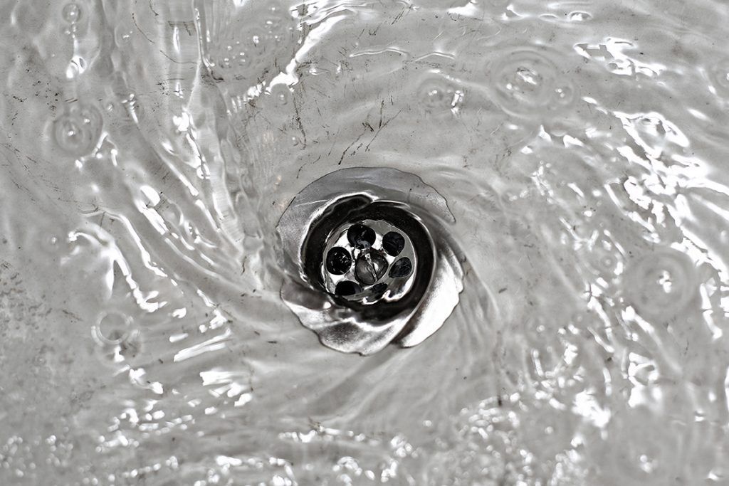 A black and white photo of water running down a sink drain.